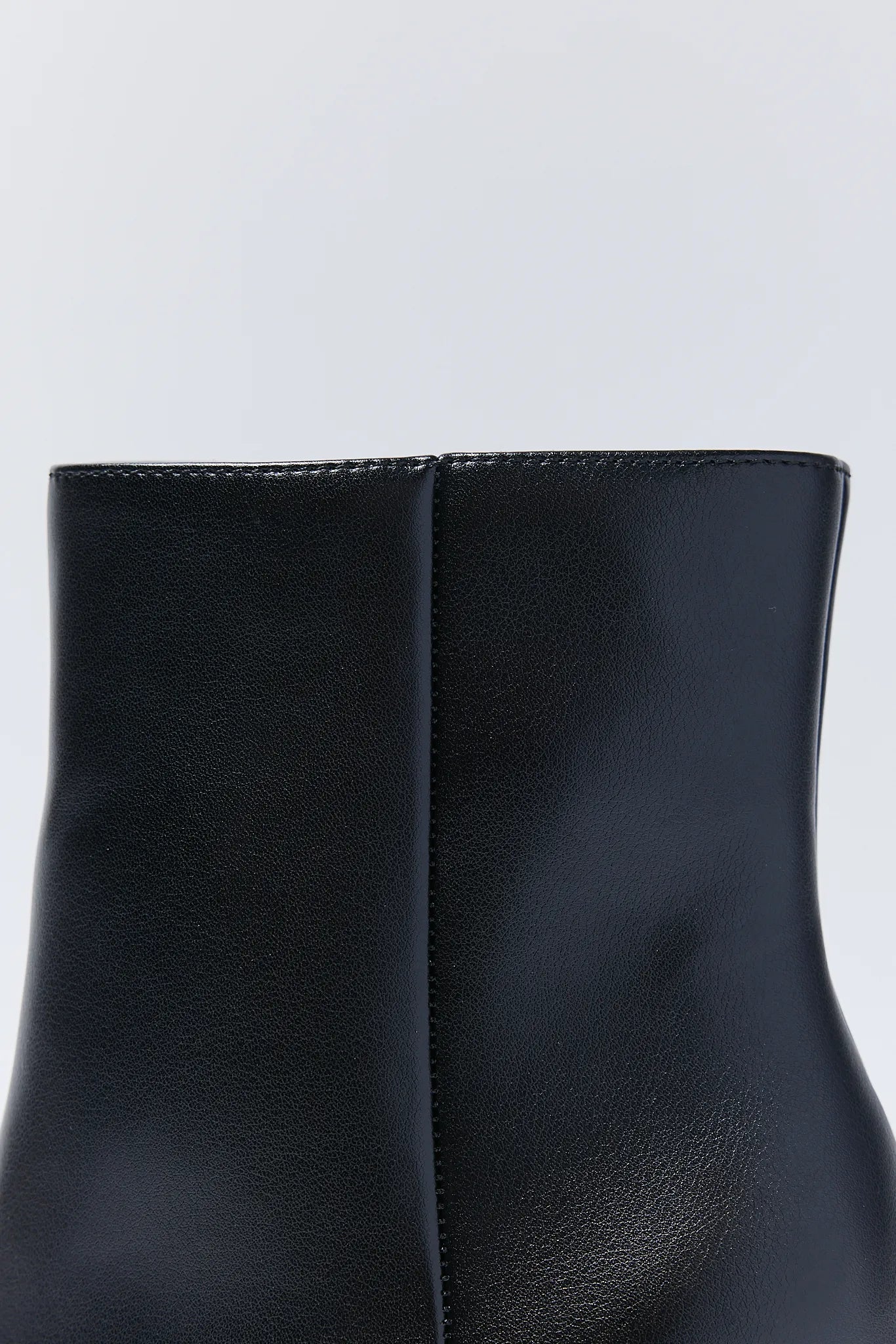Close-up of a black leather ankle Emery Boots on a light gray background