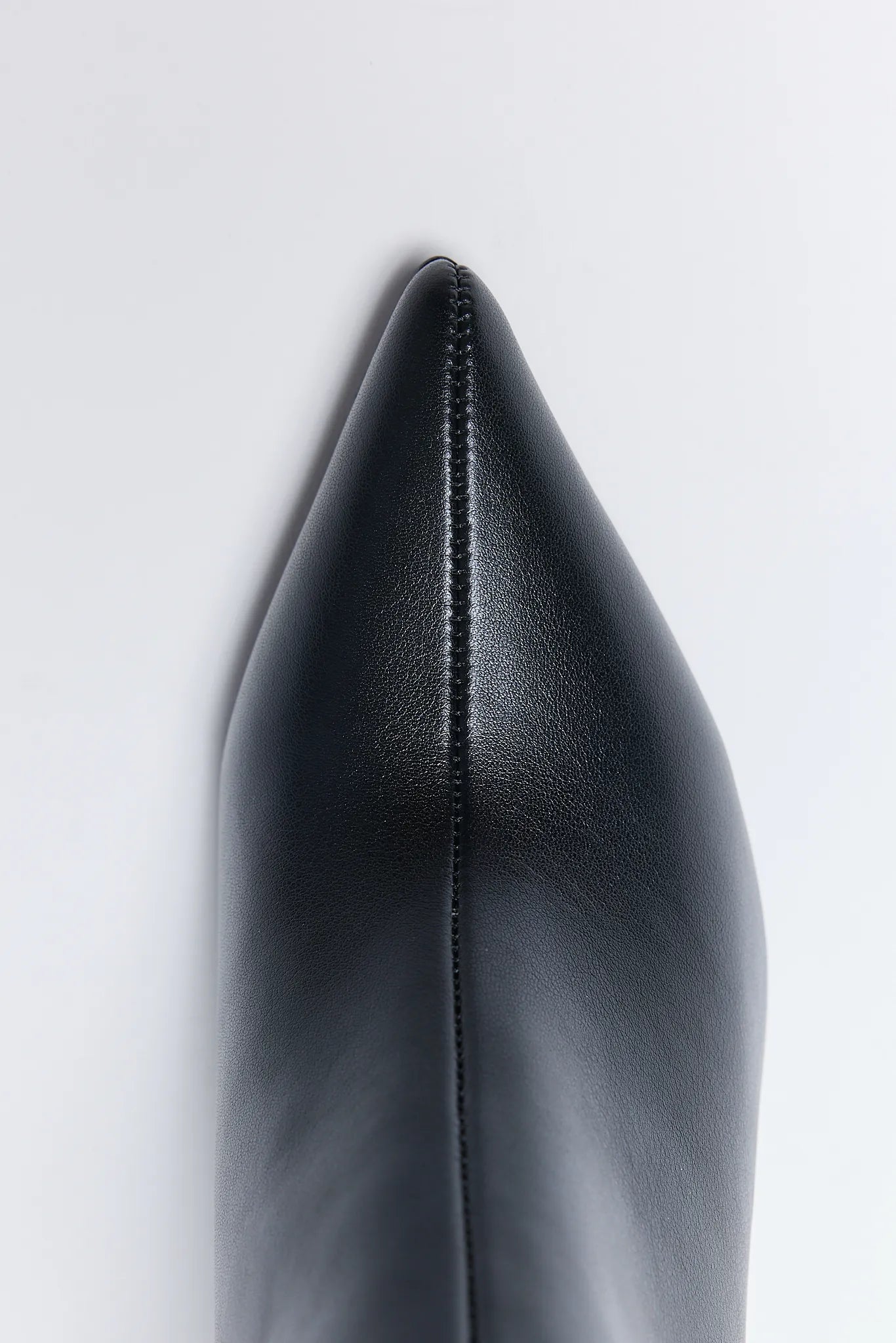Close-up of a black pointed-toe Emery Boots on a light gray background