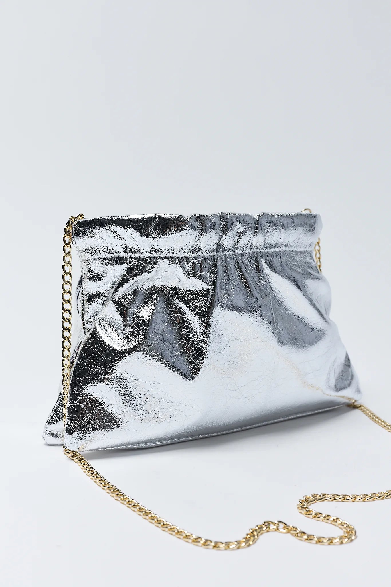 Silver clutch bag with chain strap on a light gray background