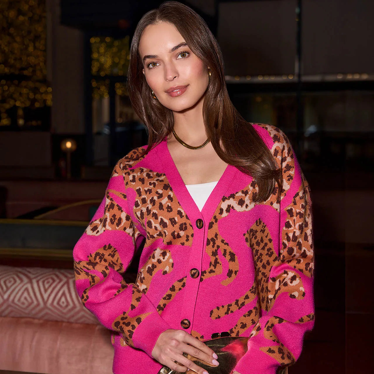 Woman wearing a pink cardigan with leopard print patterns indoors.
