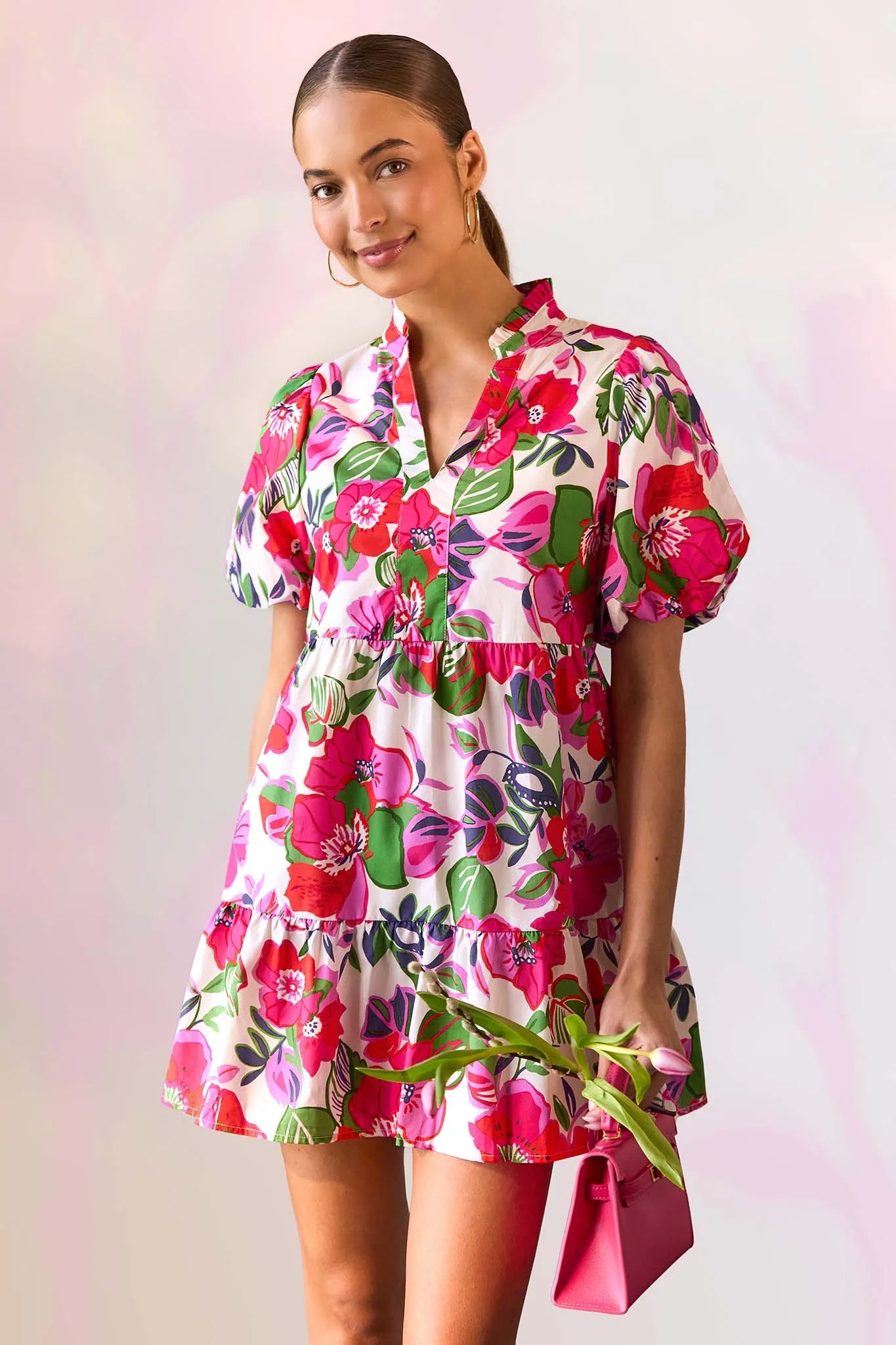 Woman wearing a colorful floral dress against a light pink background