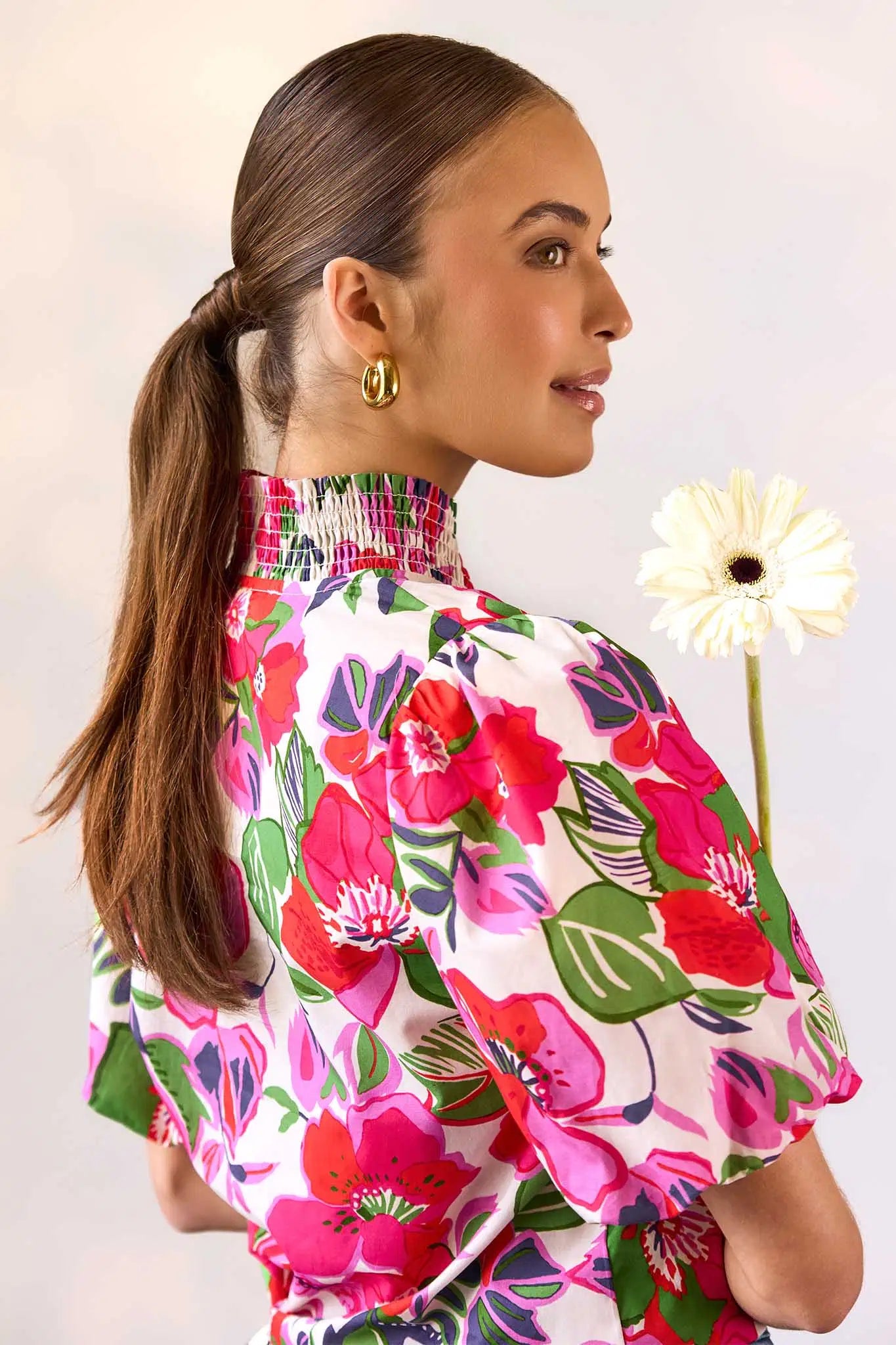 Woman wearing a colorful floral blouse with a white background