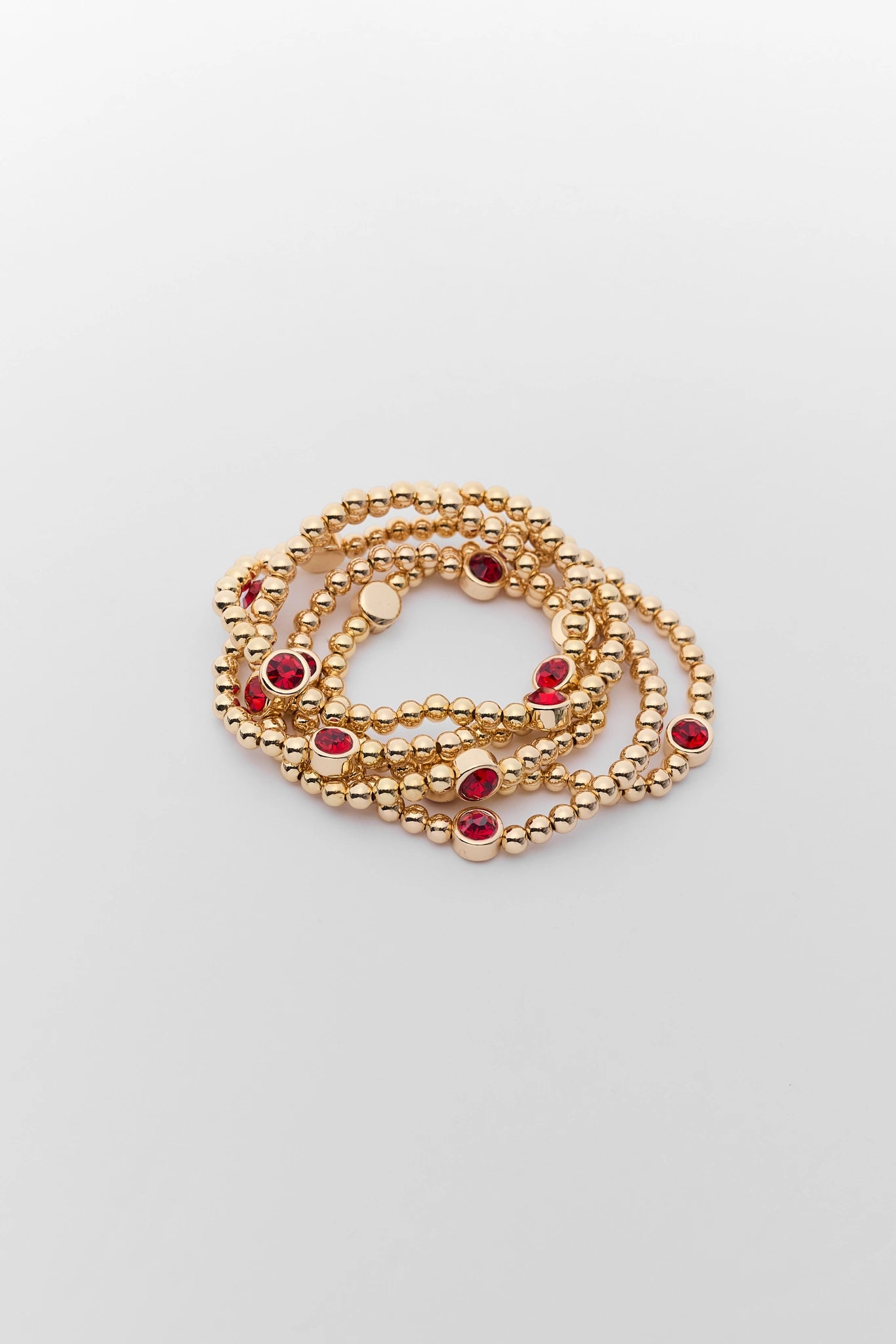 Gold Beaded Red Rhinestone Bracelet stack on a white background