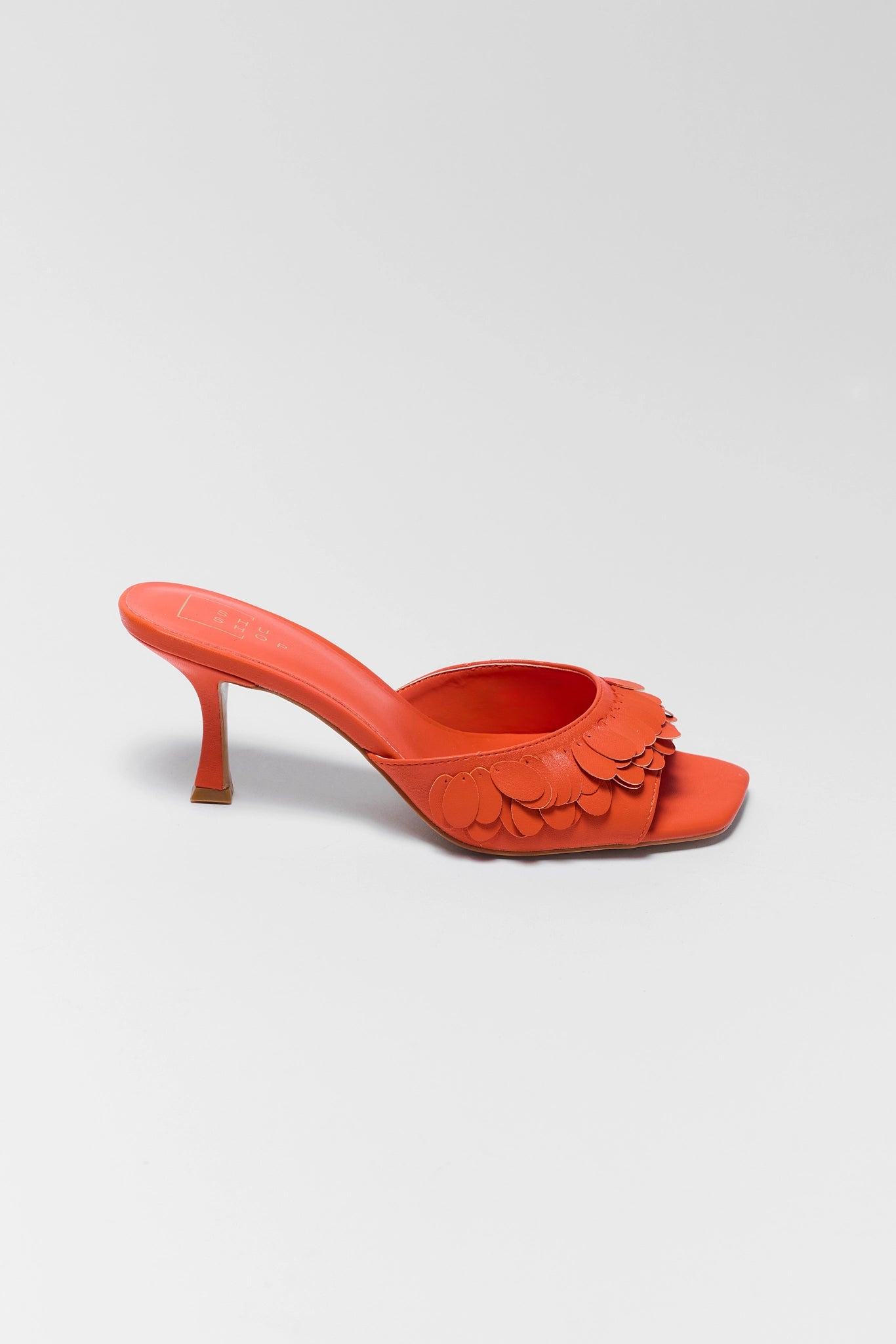 one Orange high-heeled shoe with floral design on a light gray background