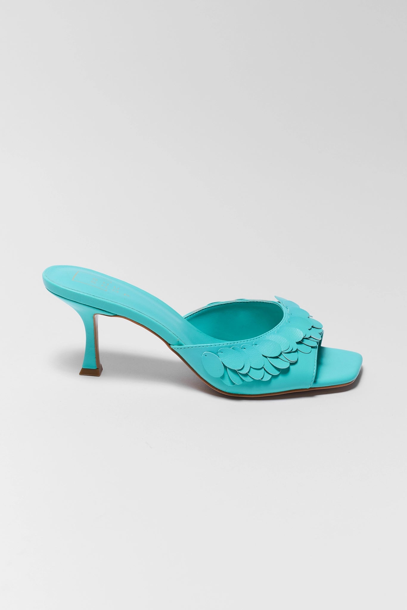 one Turquoise high-heeled shoe with scalloped edge on a light gray background