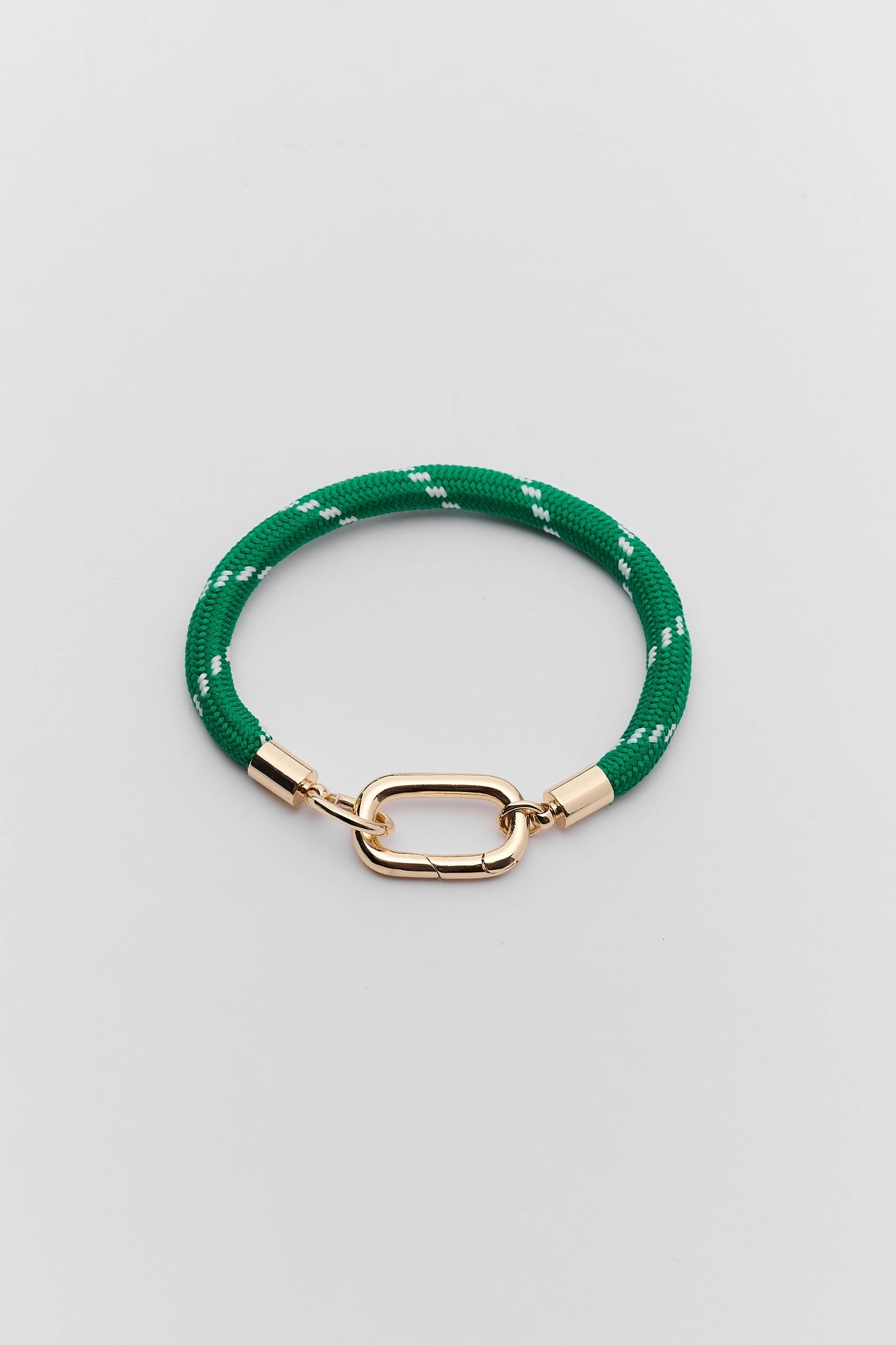 A green braided rope bracelet with a polished gold-tone oval clasp and matching gold end caps, displayed on a neutral light gray background.