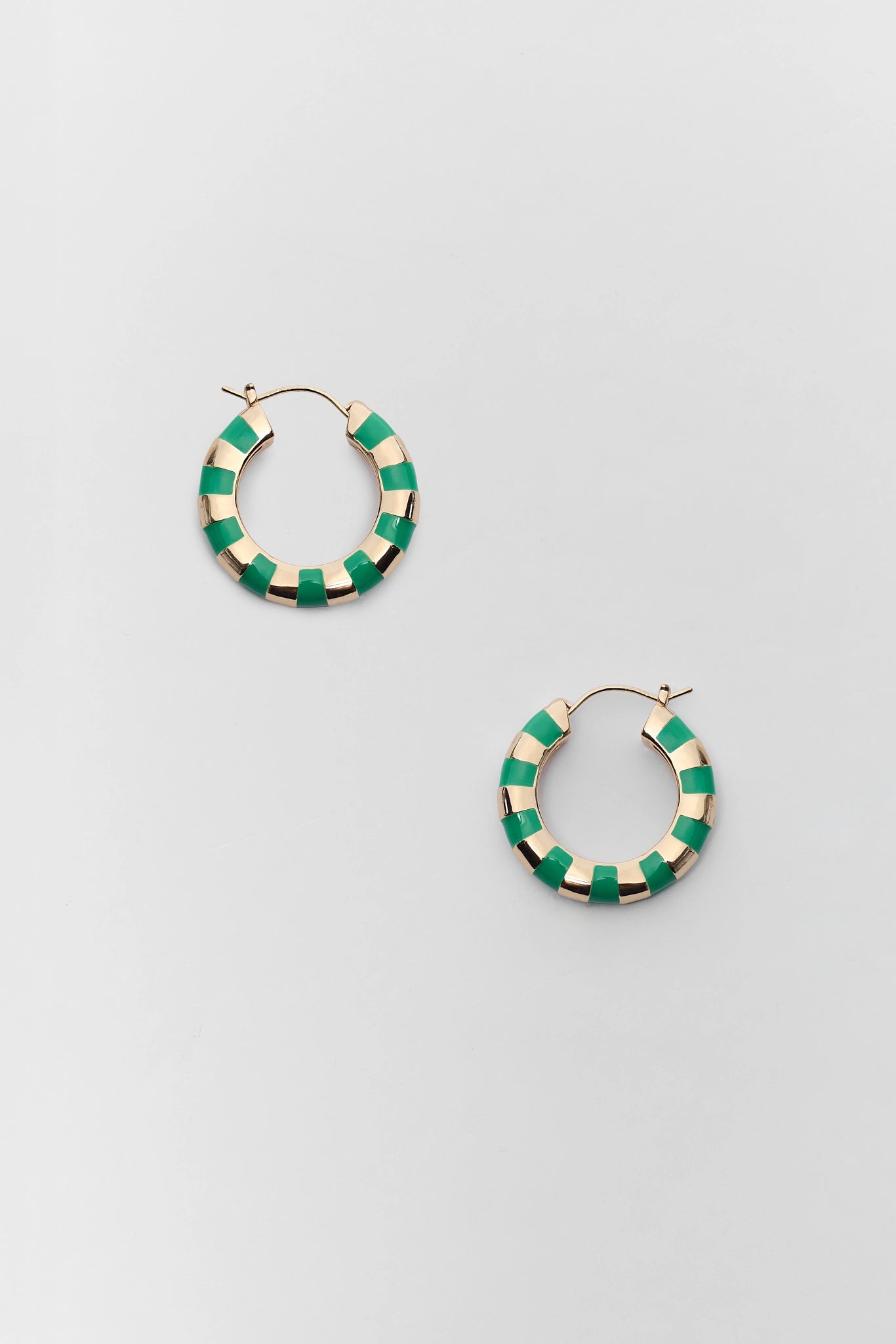 A pair of gold hoop earrings with alternating green and cream enamel segments, displayed on a light gray background.