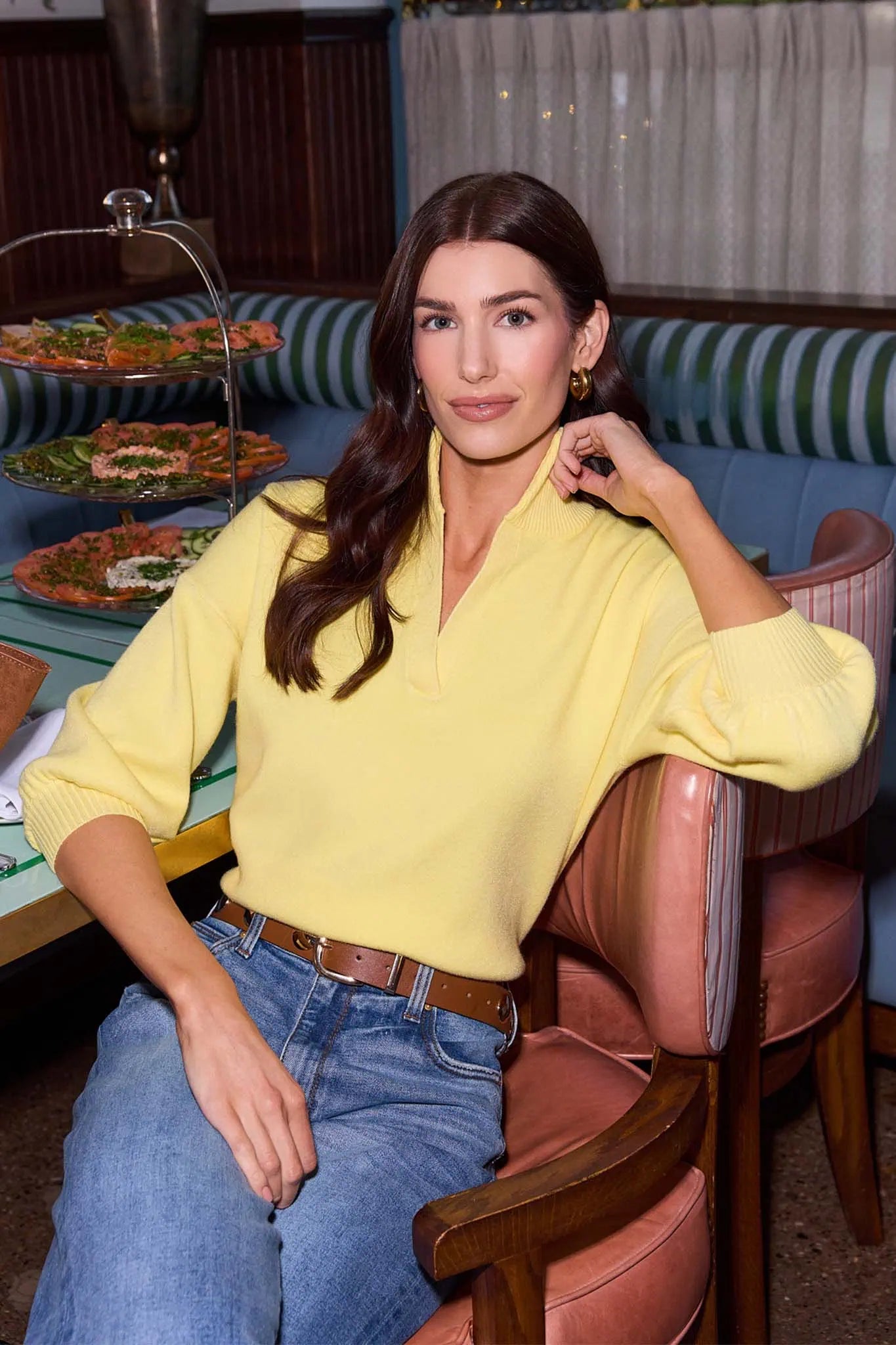 woman wearing yellow sweater and jeans sitting at table