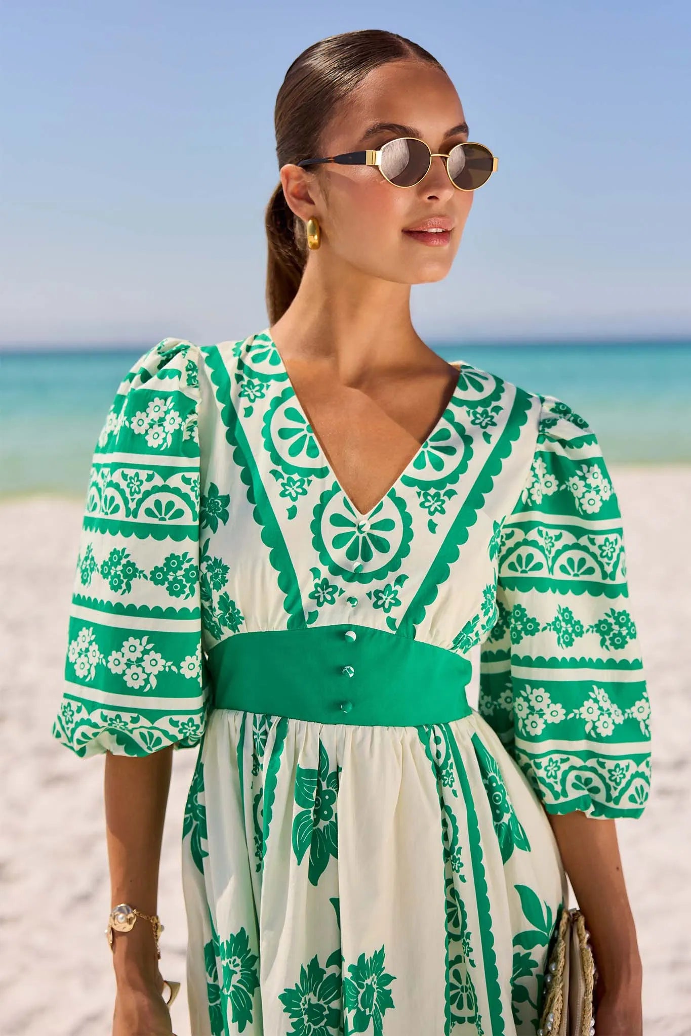 close up Woman in a green and white patterned dress on a beach