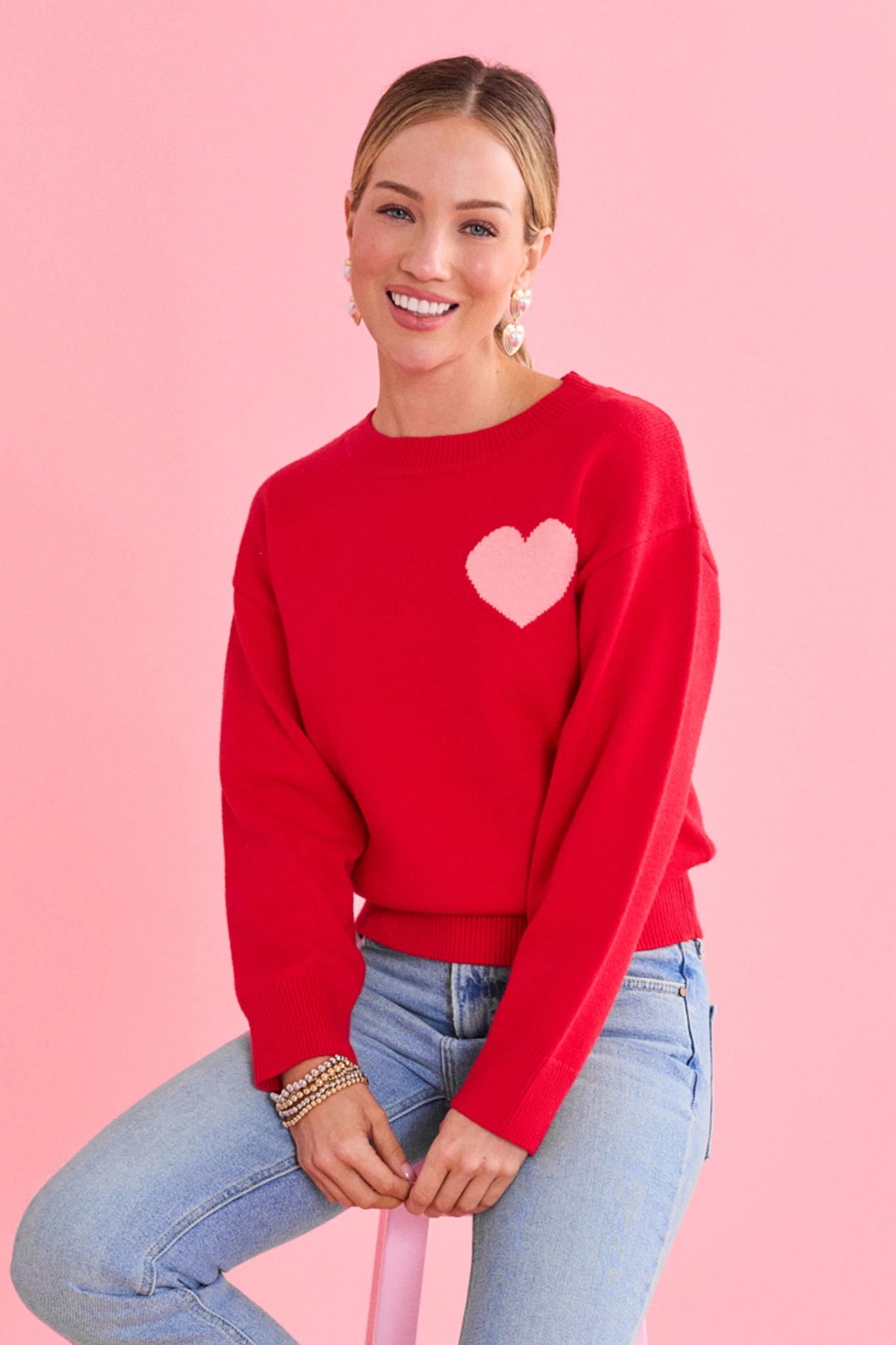woman wearing red sweater with pink heart on a pink background