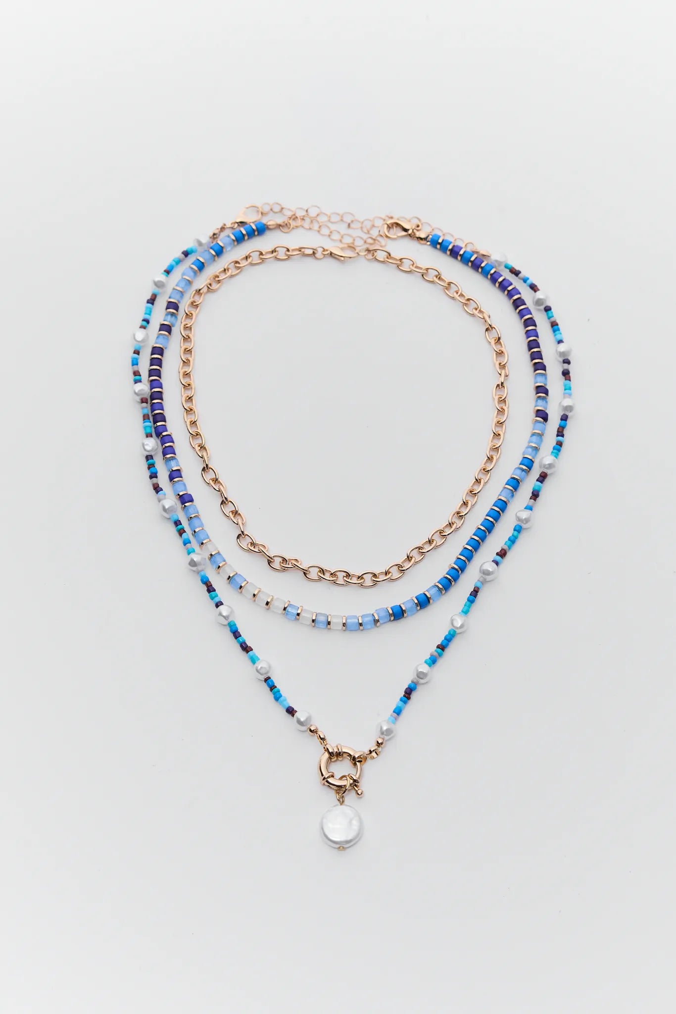 Set of three beaded necklaces on a light gray background