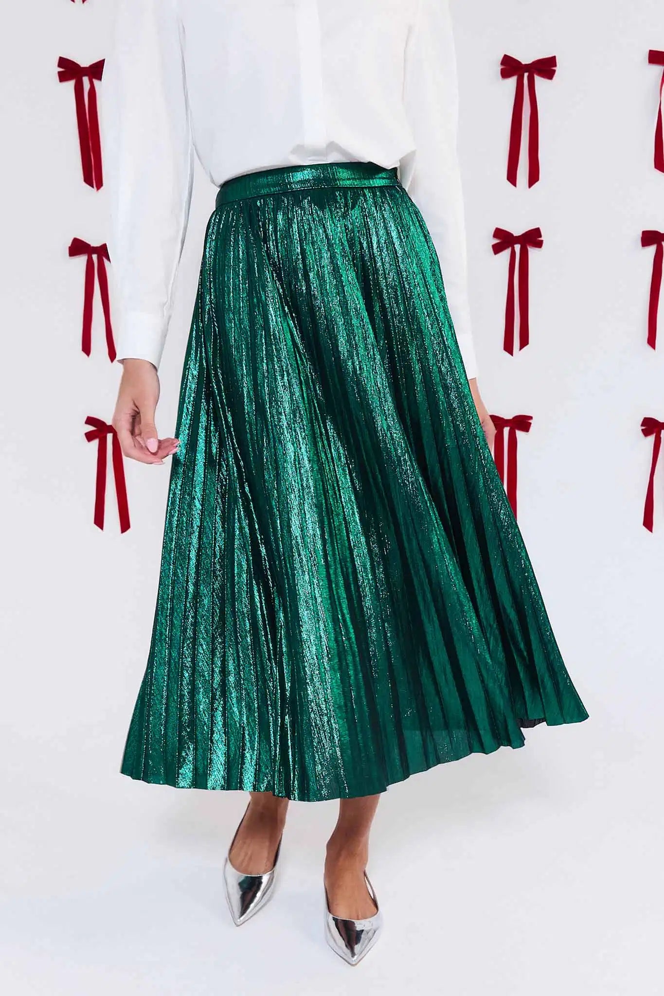 Green pleated skirt worn with a white top against a background with red bows.