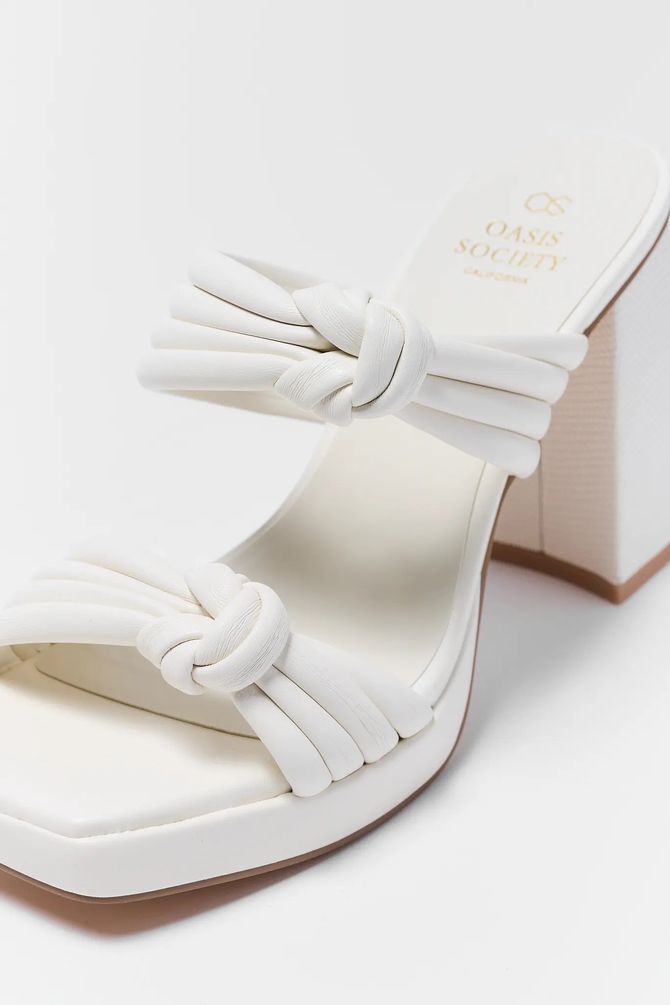 White sandal with a bow detail on a white background