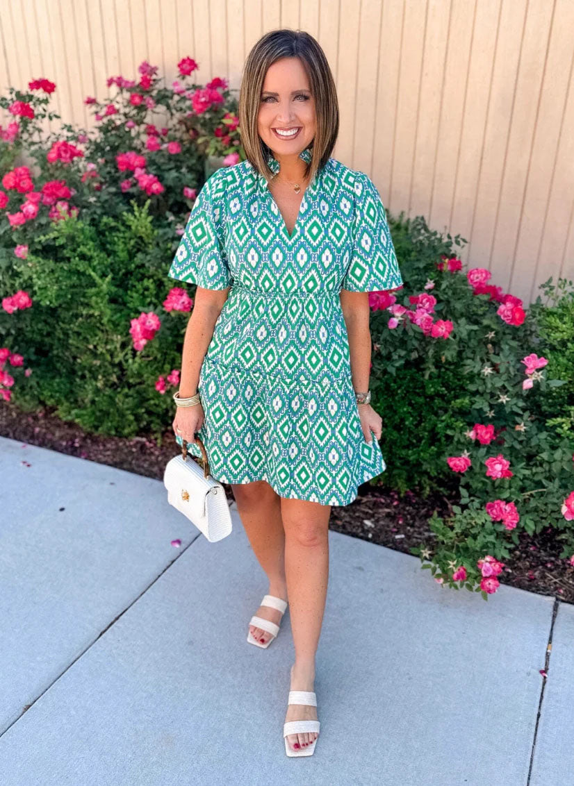 women in green patterned dress with flowers in background