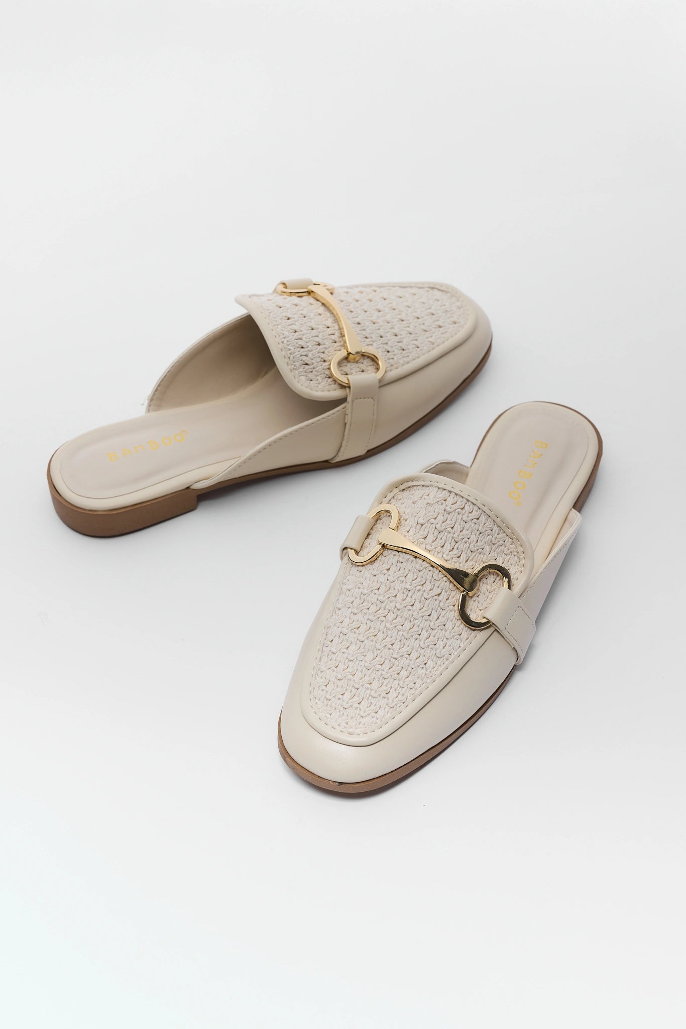 Pair of beige loafers with gold accents on a white background