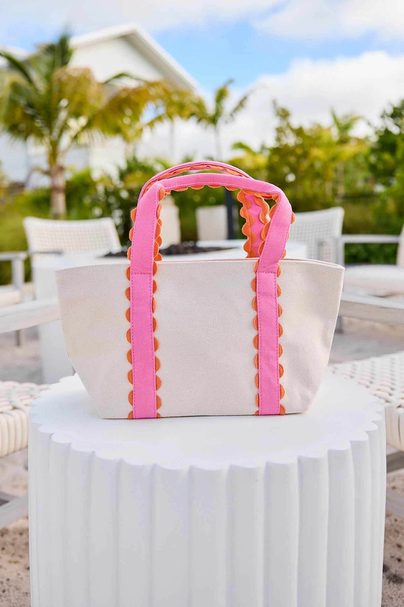 White bag with pink and yellow handles on a white surface outdoors