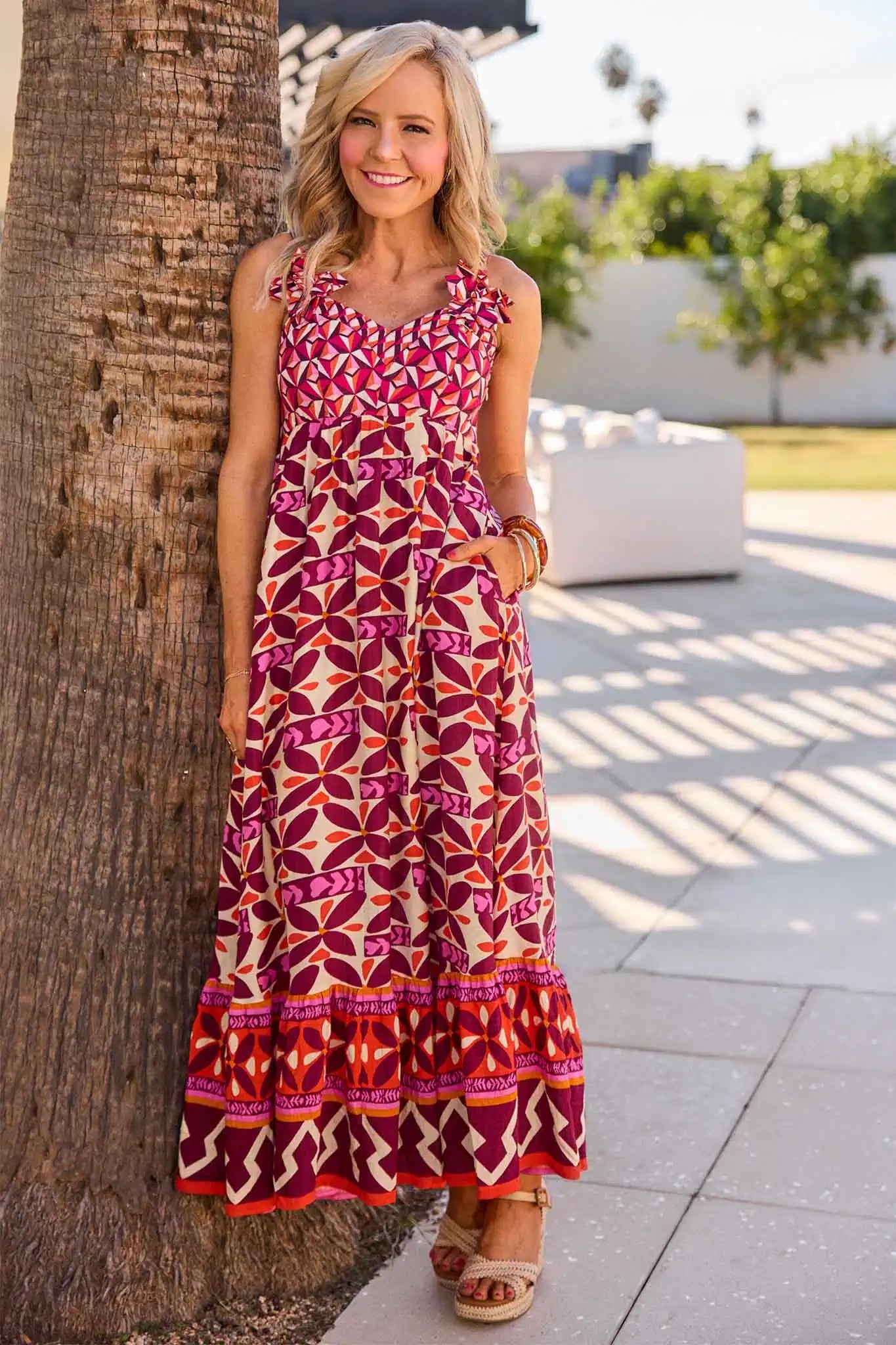 Woman in a Jackie Pink Printed Midi Dress standing next to a palm tree