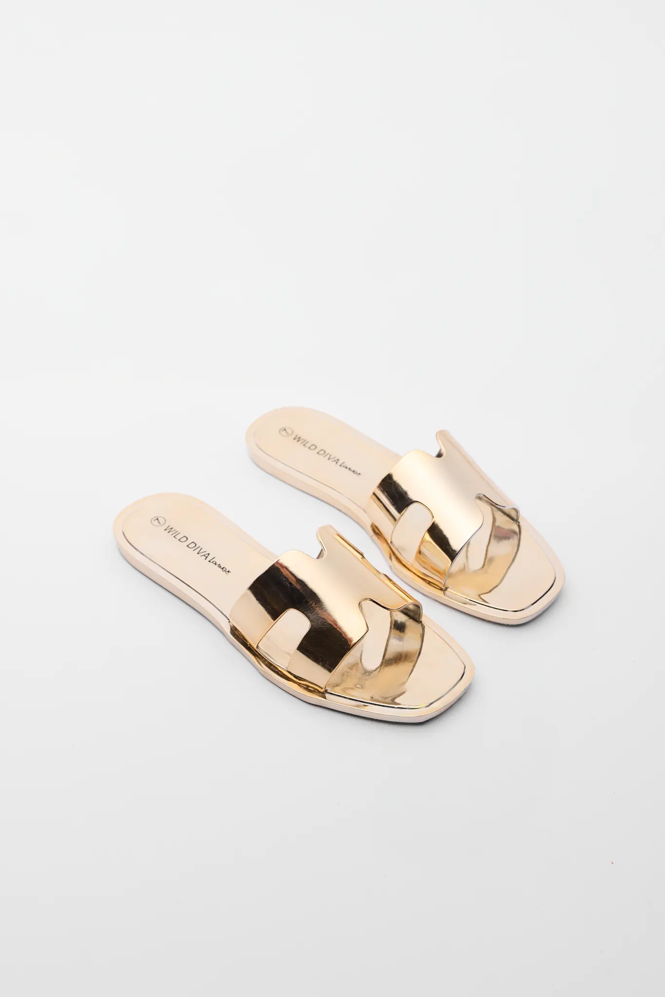 Pair of shiny gold sandals on a light gray background