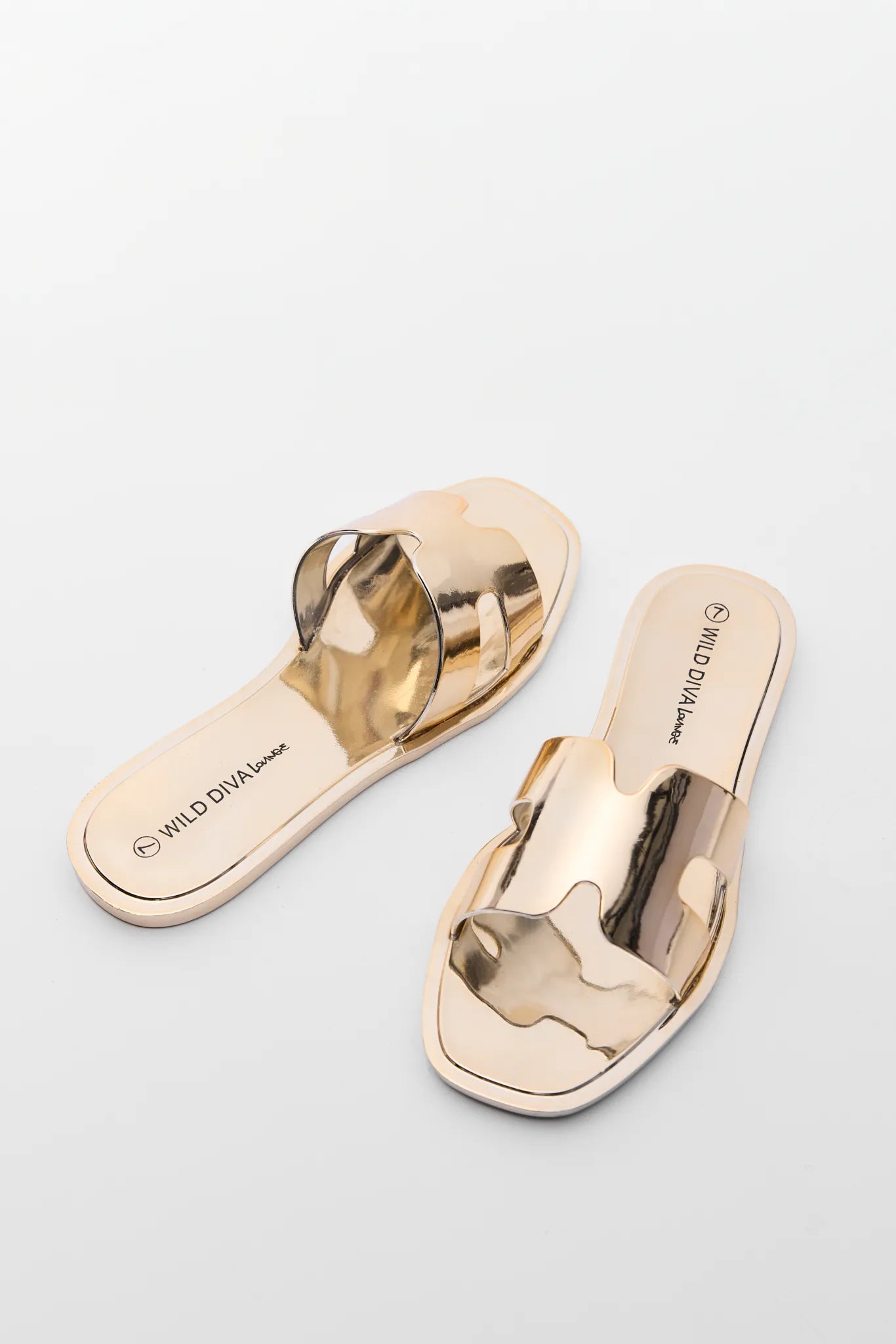 Pair of gold flip-flops on a light gray background