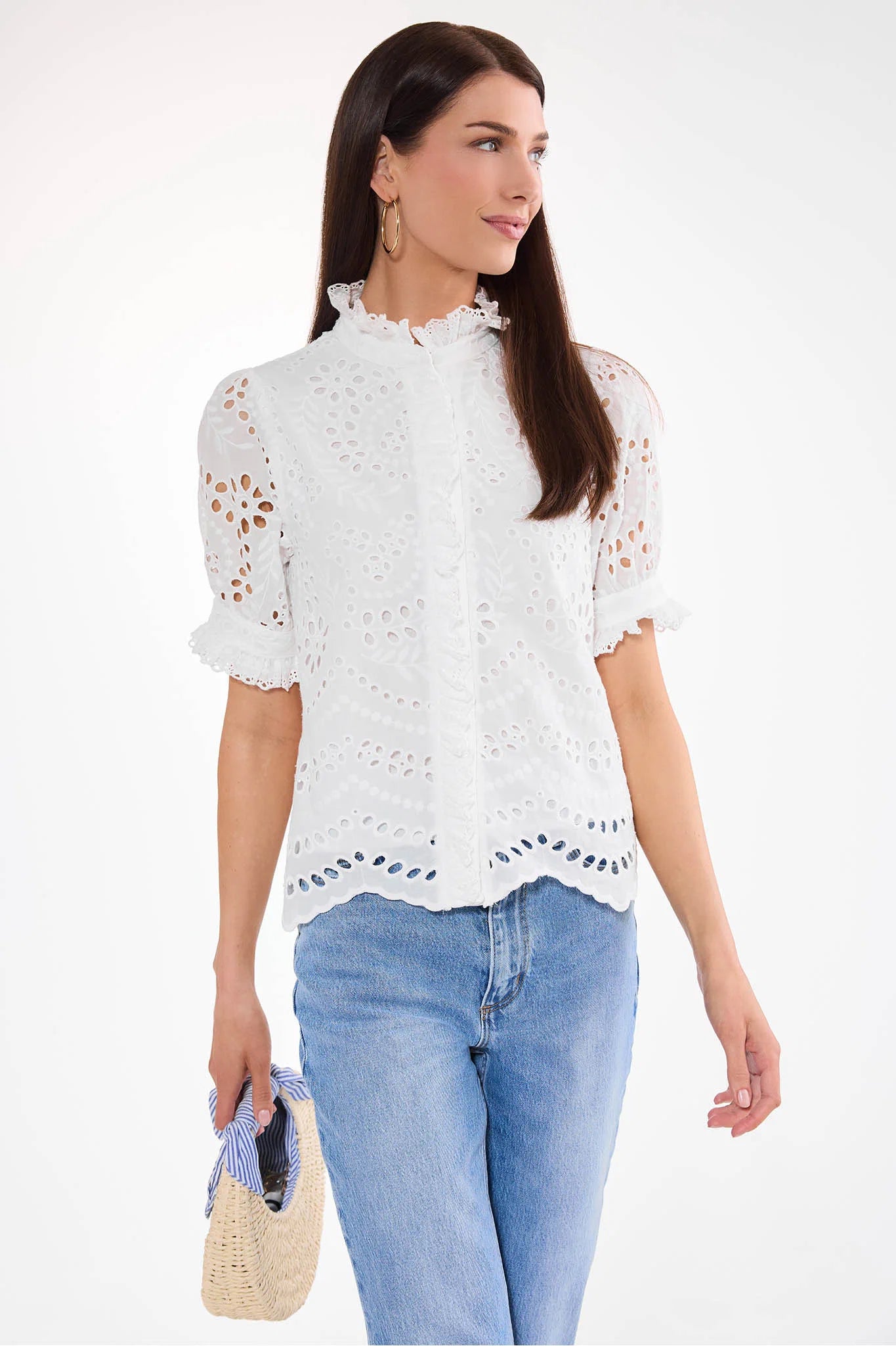 Woman wearing a white lace blouse and blue jeans on a white background