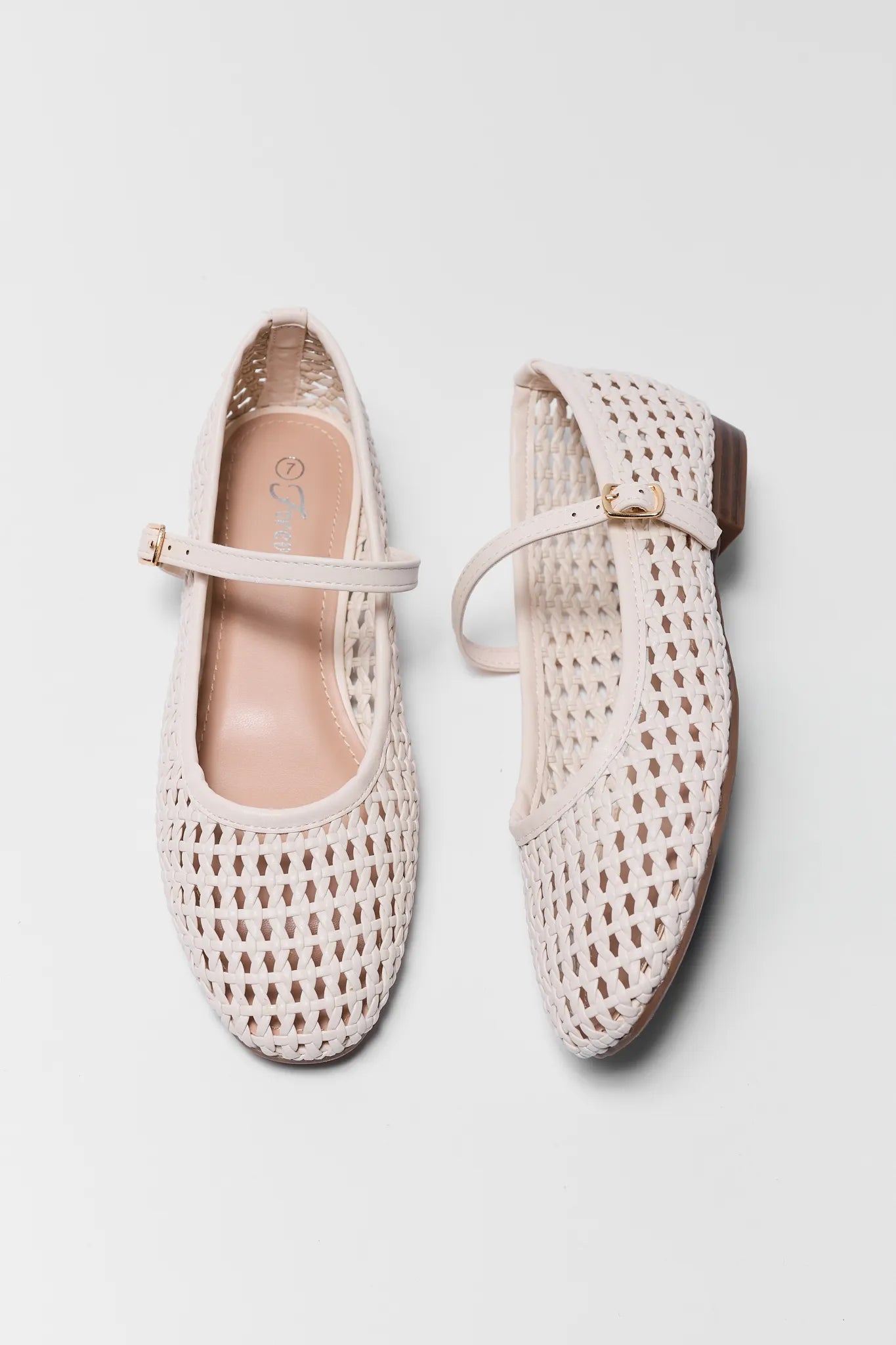 Pair of beige woven shoes with strap on a light gray background