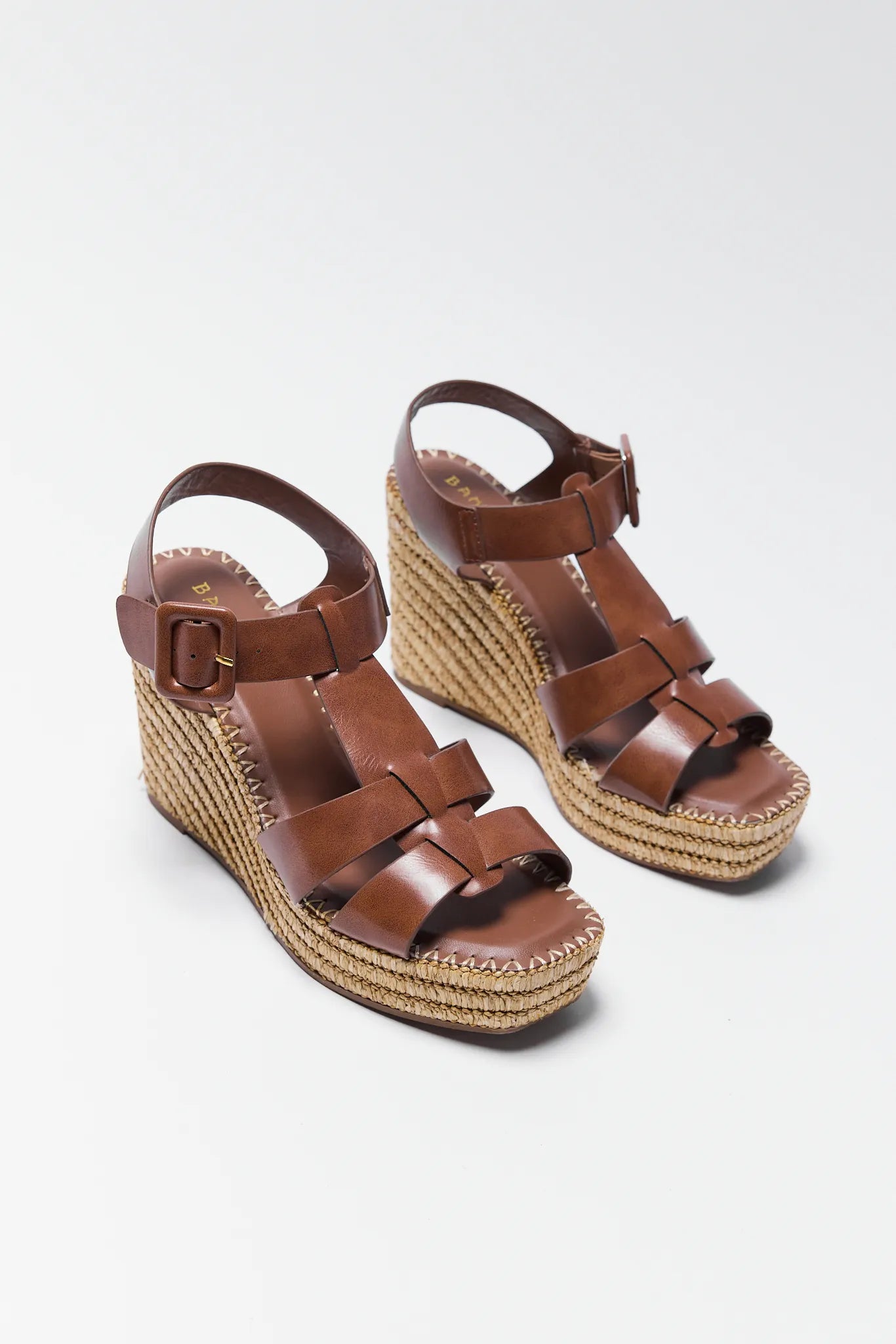 Brown wedge sandals with espadrille sole on a light gray background