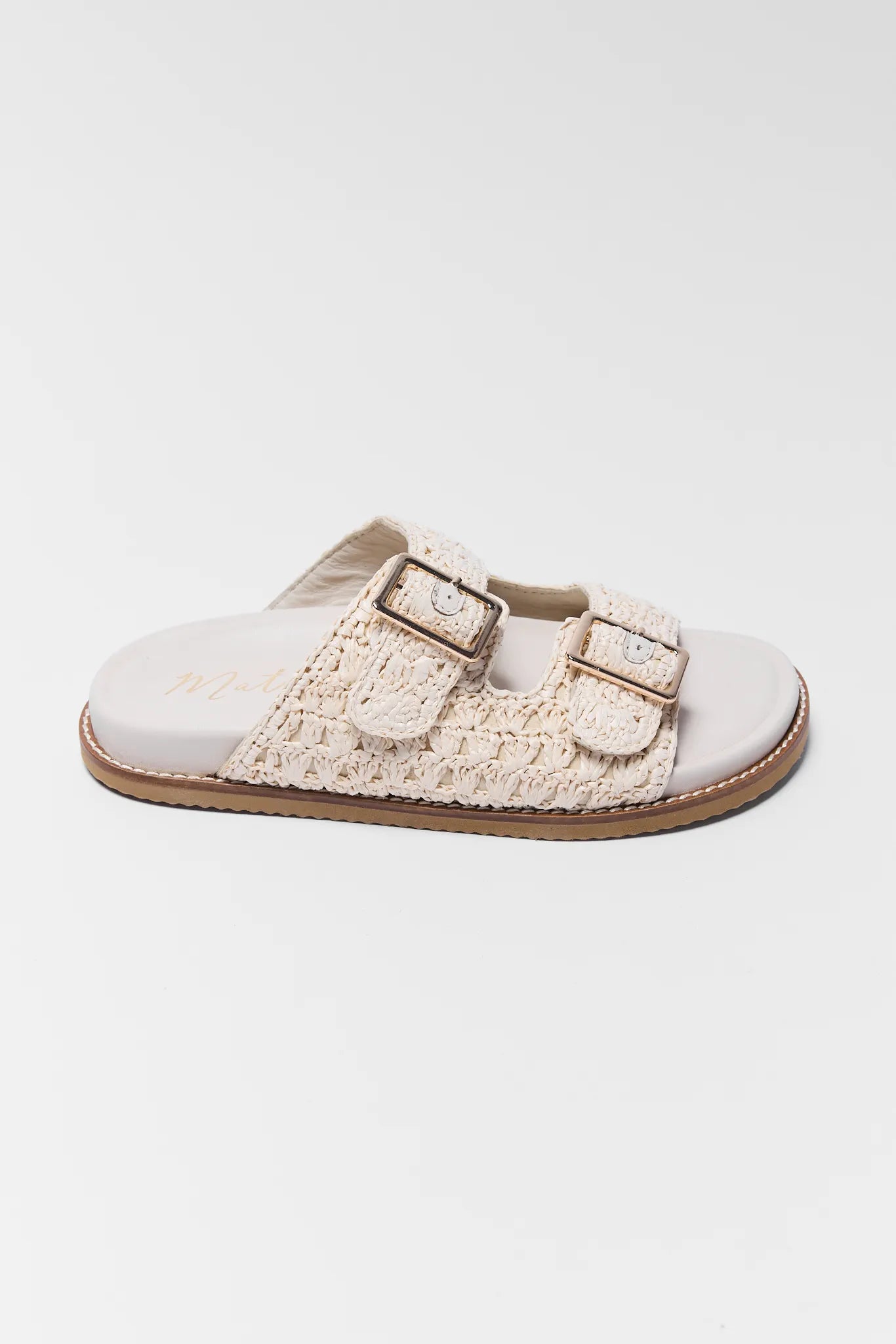 White sandal with beige woven strap and buckles on a white background