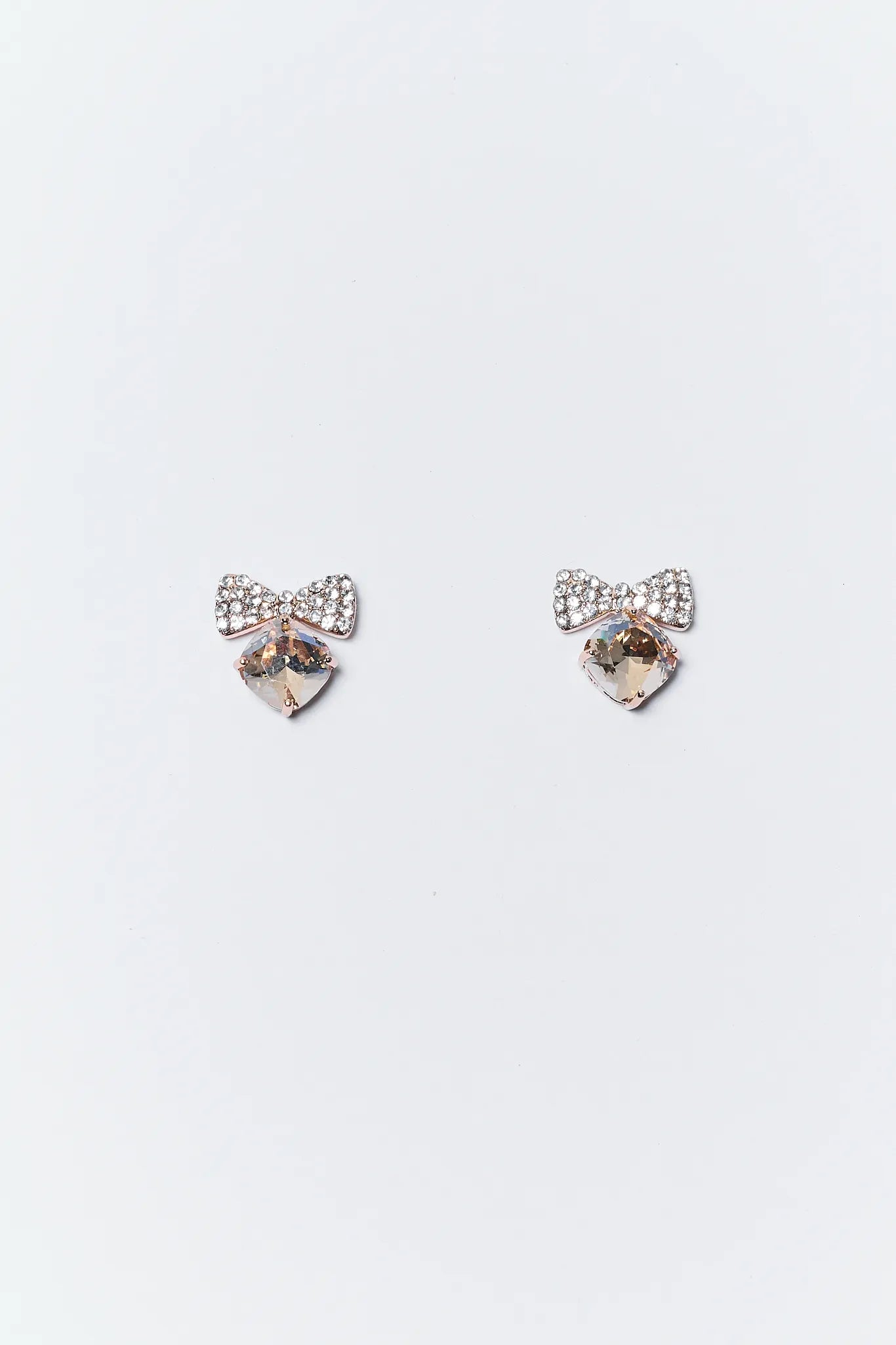 Pair of heart-shaped earrings with clear stones on a light gray background