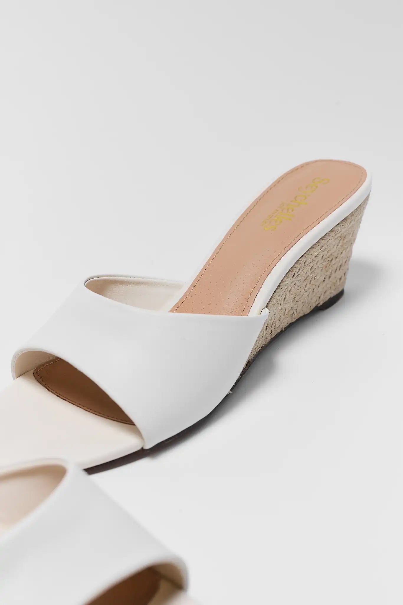 White wedge sandal on a light gray background close up
