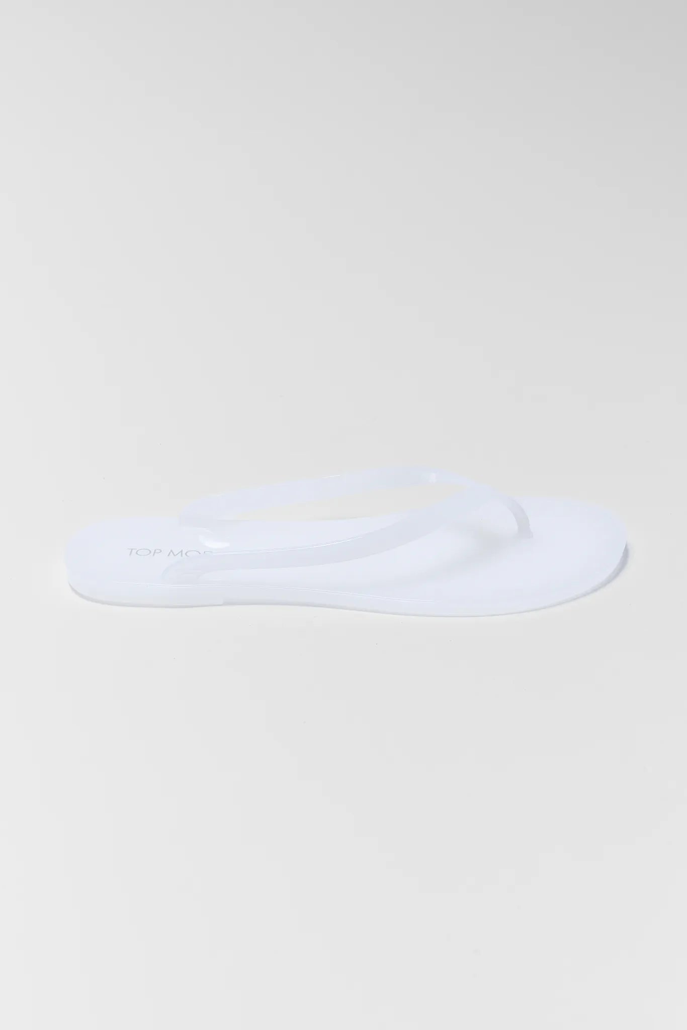 White flip-flop sandal on a light beige background
