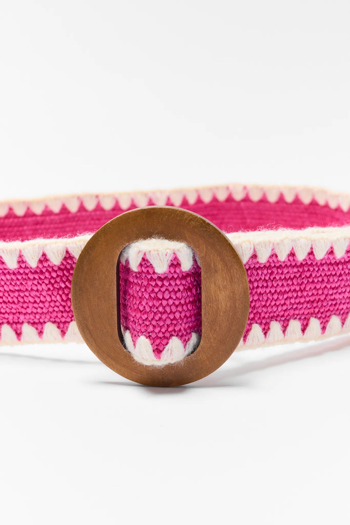 close up Pink and white striped fabric belt with a wooden buckle on a white background