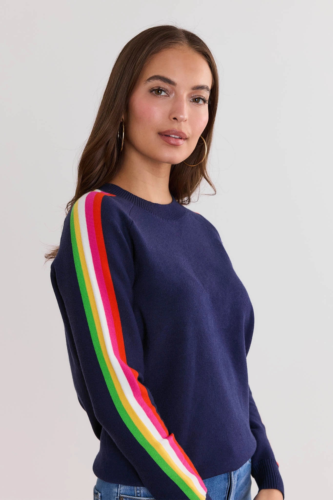 Woman wearing a Khloe Navy Striped Sleeve Sweater with colorful stripes on a plain background
