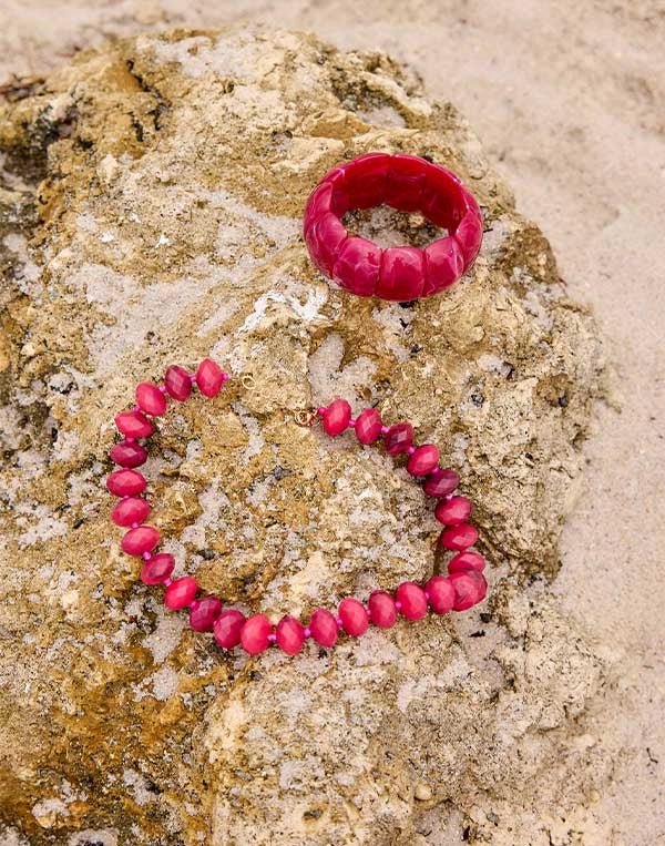 Pink beaded bracelet and ring on a textured stone surface