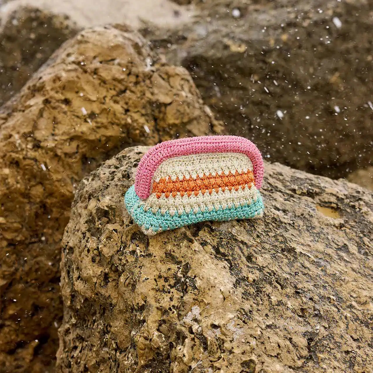 Colorful crocheted bar of soap on a rock with a natural background