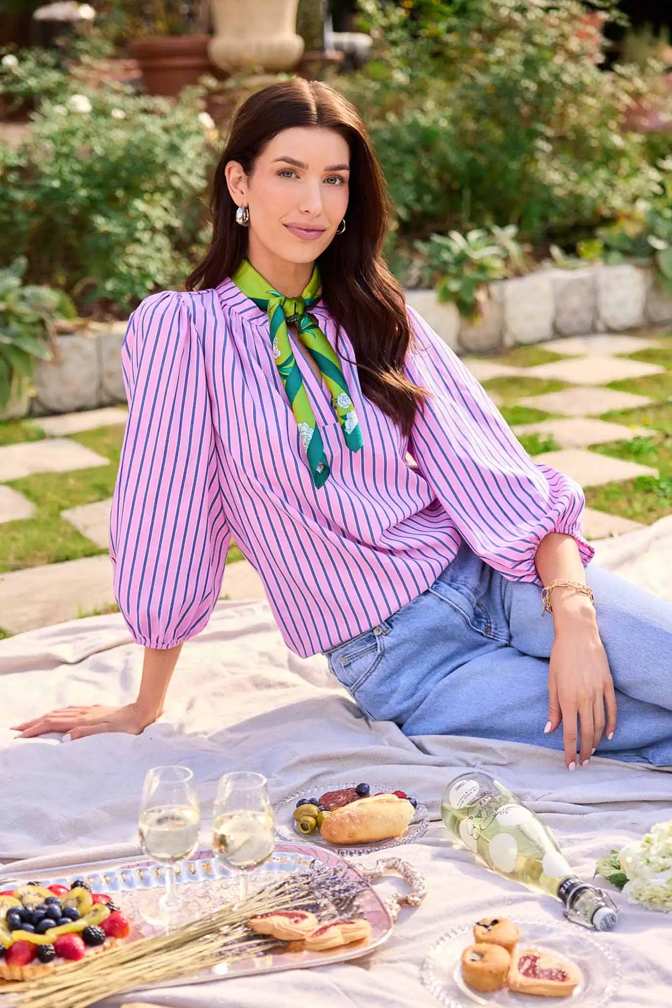 Woman sitting on a blanket with a picnic setup in a garden