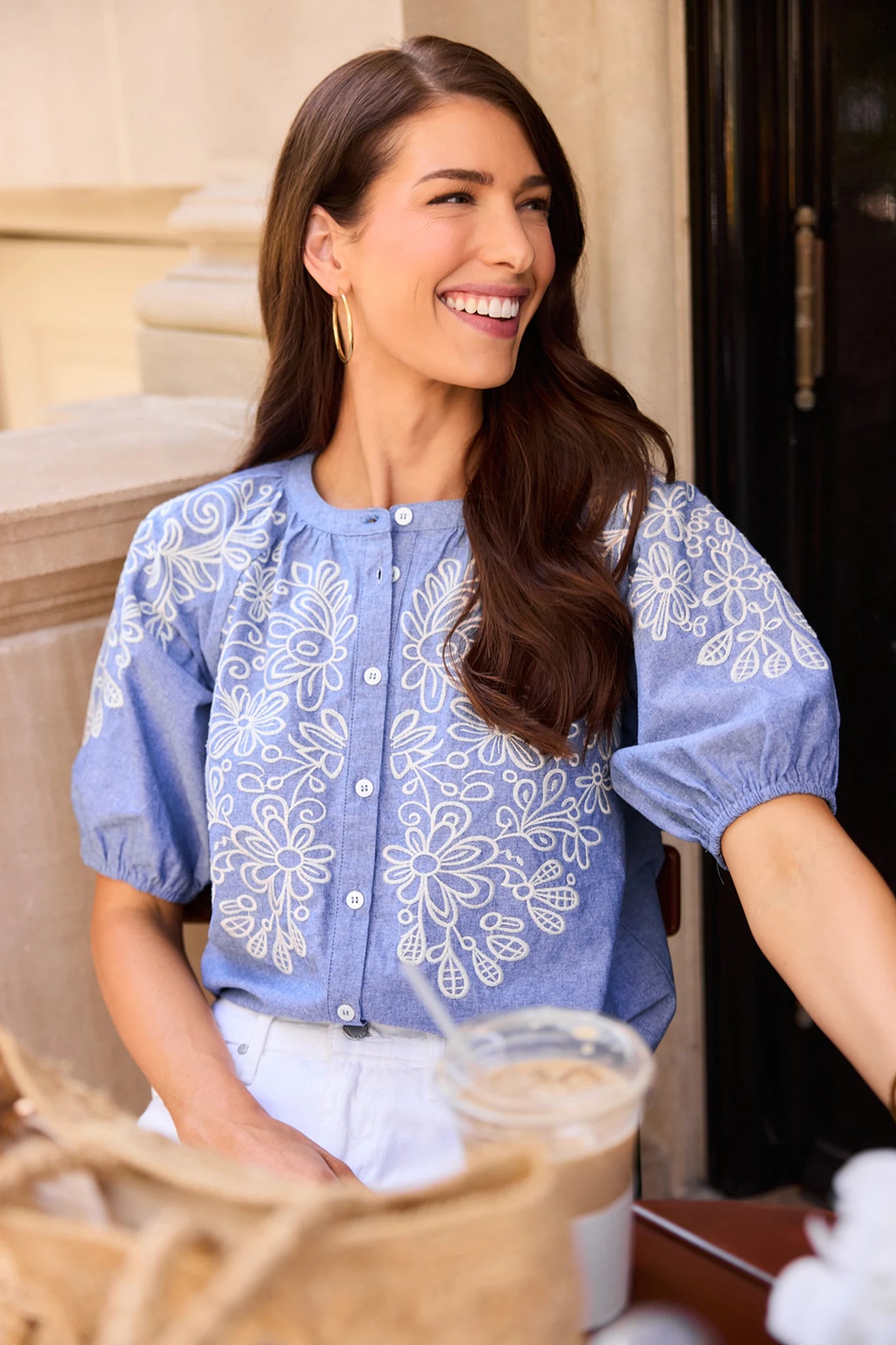 Woman wearing a blue floral patterned blouse sitting at a coffee shop