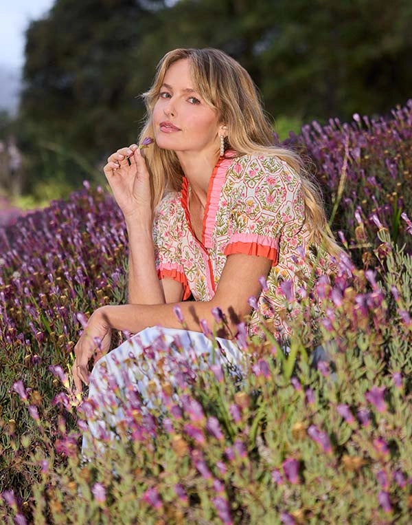 Woman in a floral dress sitting among lavender flowers