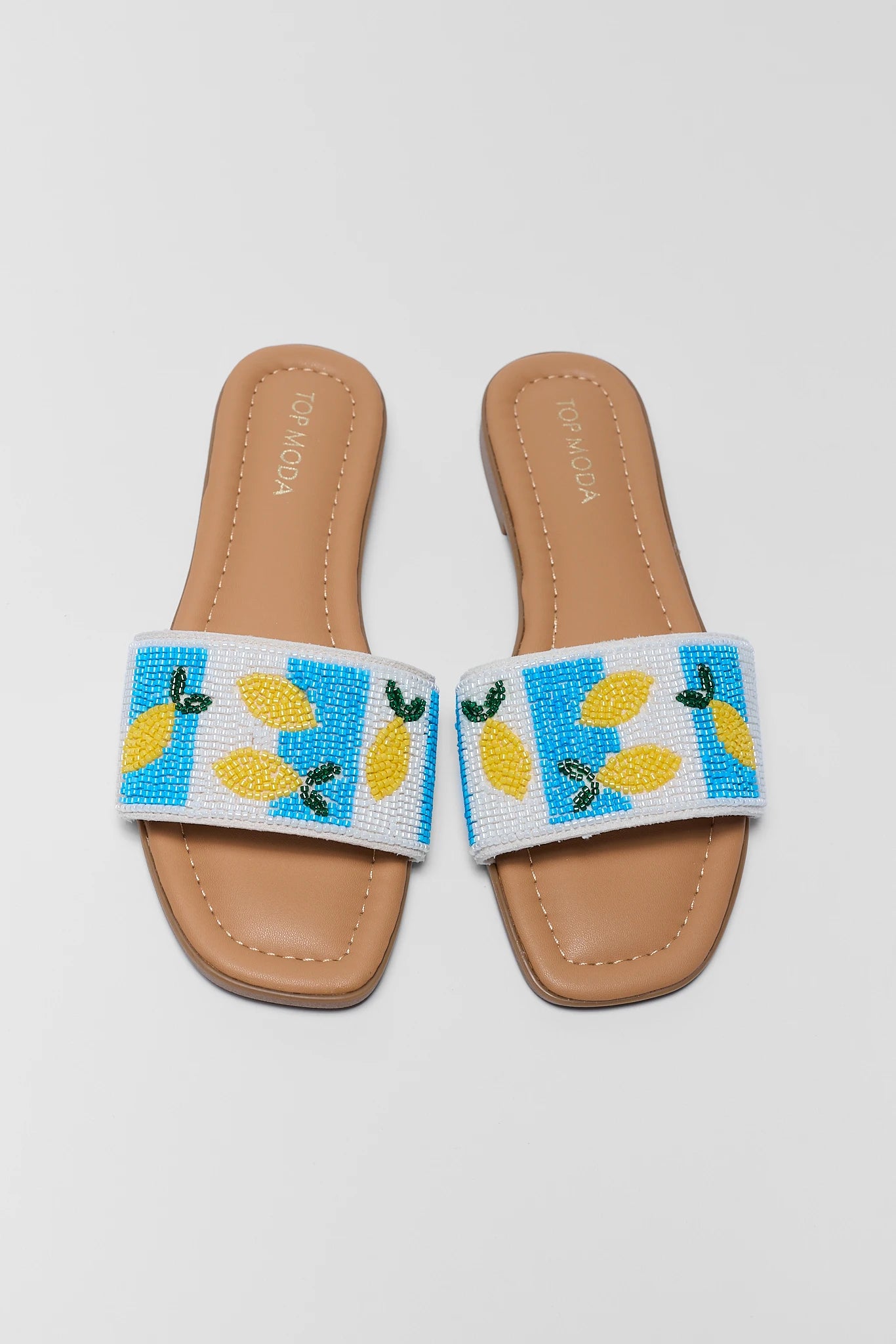 Pair of new sandals with lemon design on a light gray background