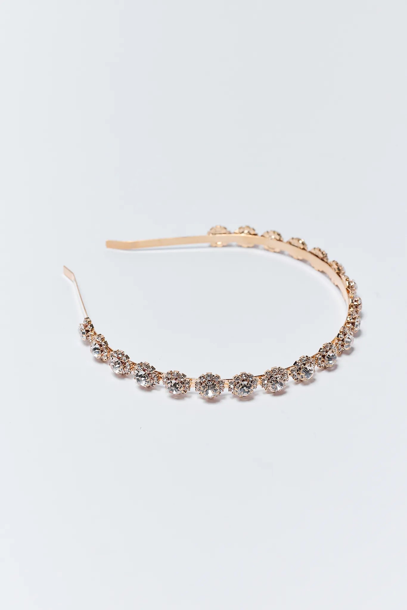 Rose gold headband with floral embellishments on a light gray background