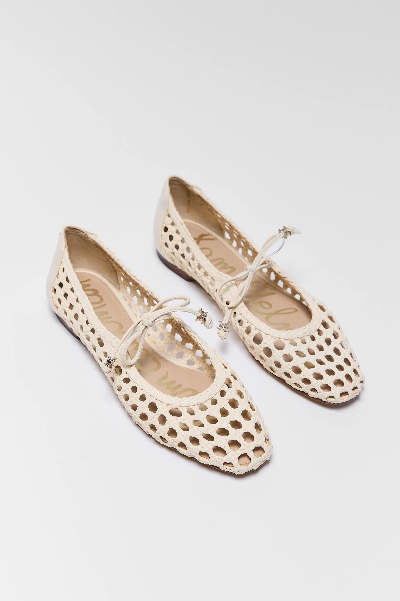 Pair of beige perforated shoes on a light gray background