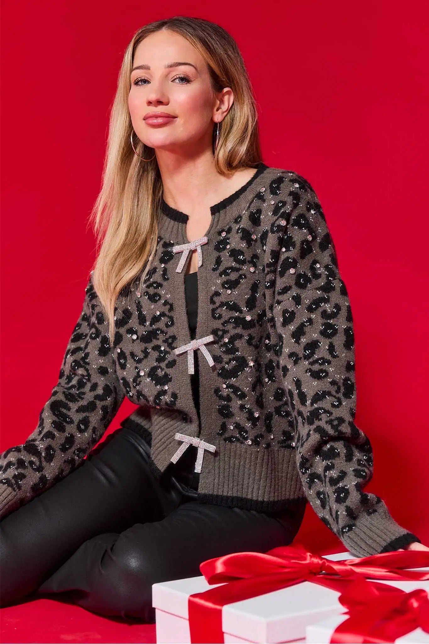 Woman wearing a marcie leopard print cardigan with a red background