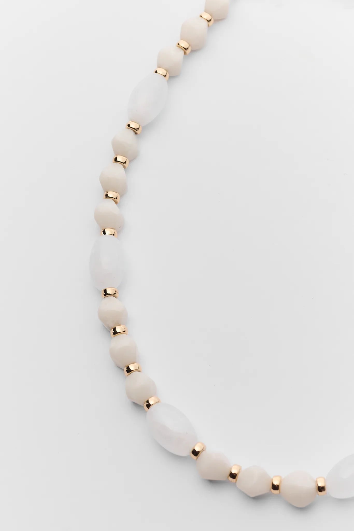 Necklace with white beads and gold accents on a light gray background