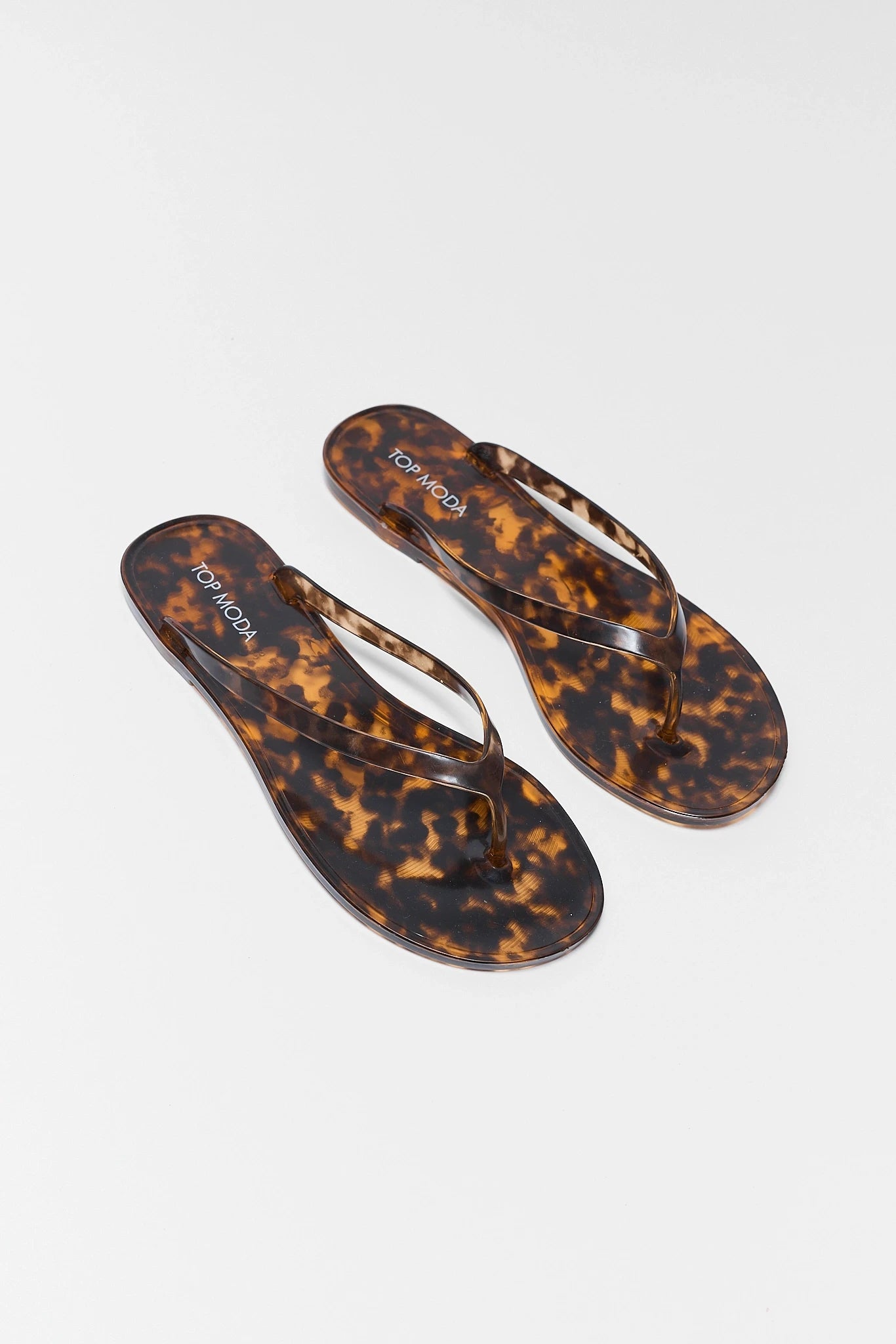 Pair of tortoiseshell flip-flops on a white background