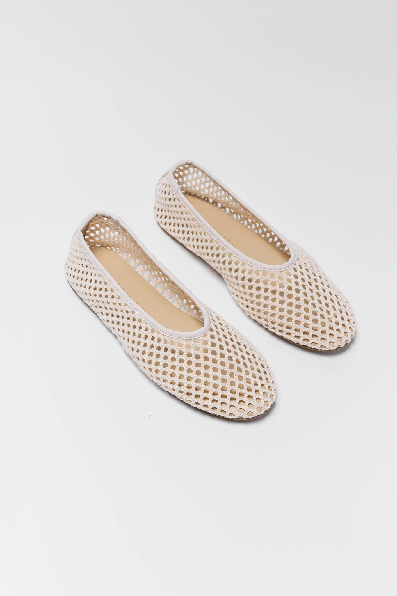 Pair of beige woven shoes on a light gray background close up