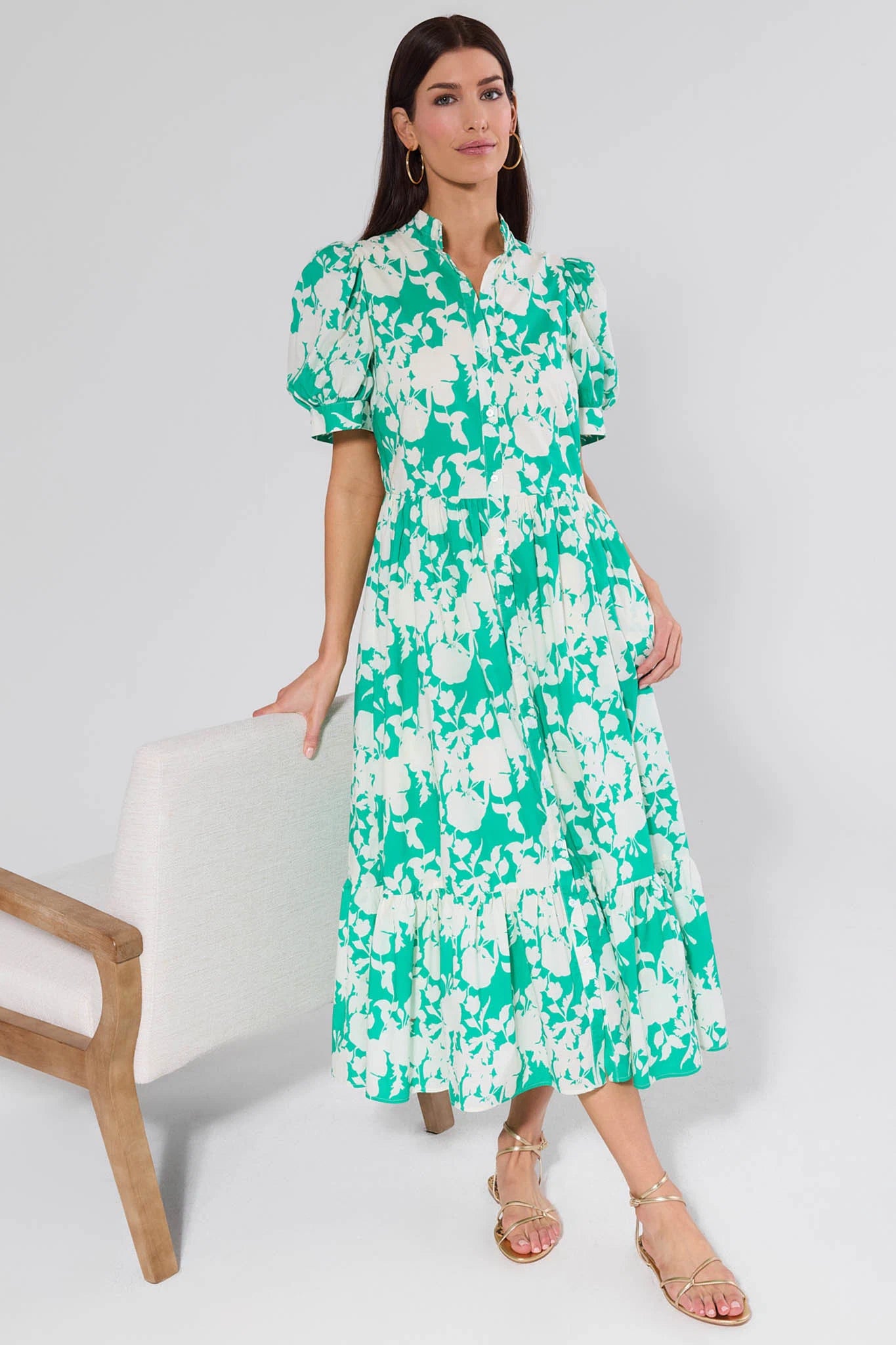 Woman wearing a green floral dress standing against a white background
