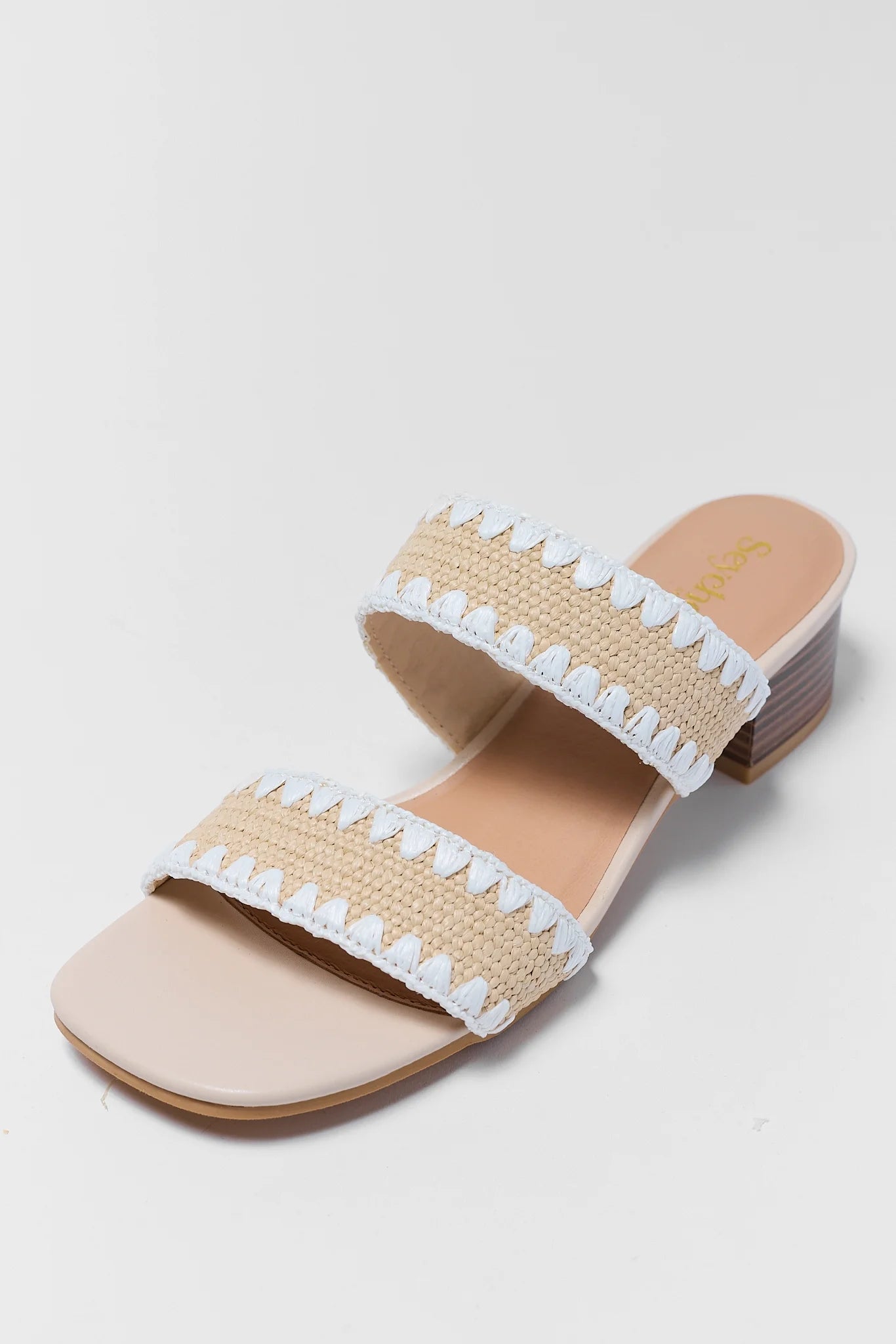 close up Beige sandals with white embellishments on a light gray background