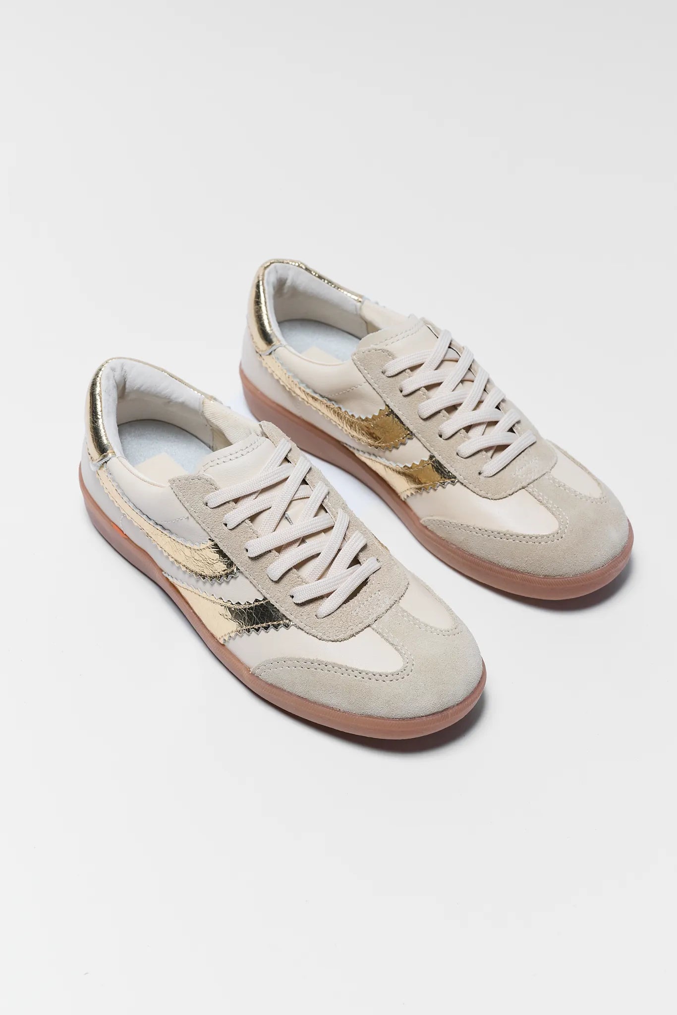 Pair of beige sneakers with gold accents on a white background