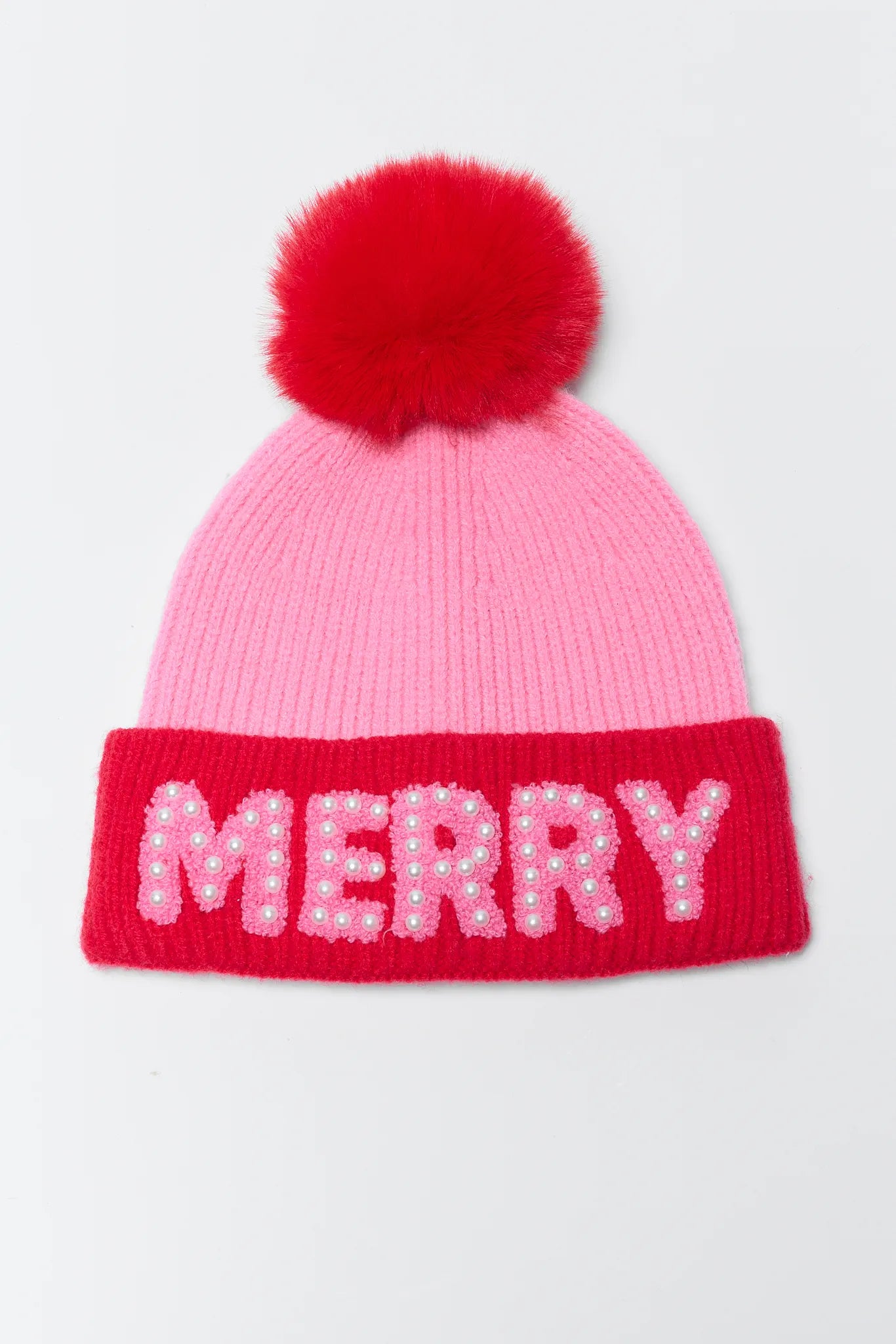 Pink beanie with red pom-pom and 'MERRY' text on a light gray background