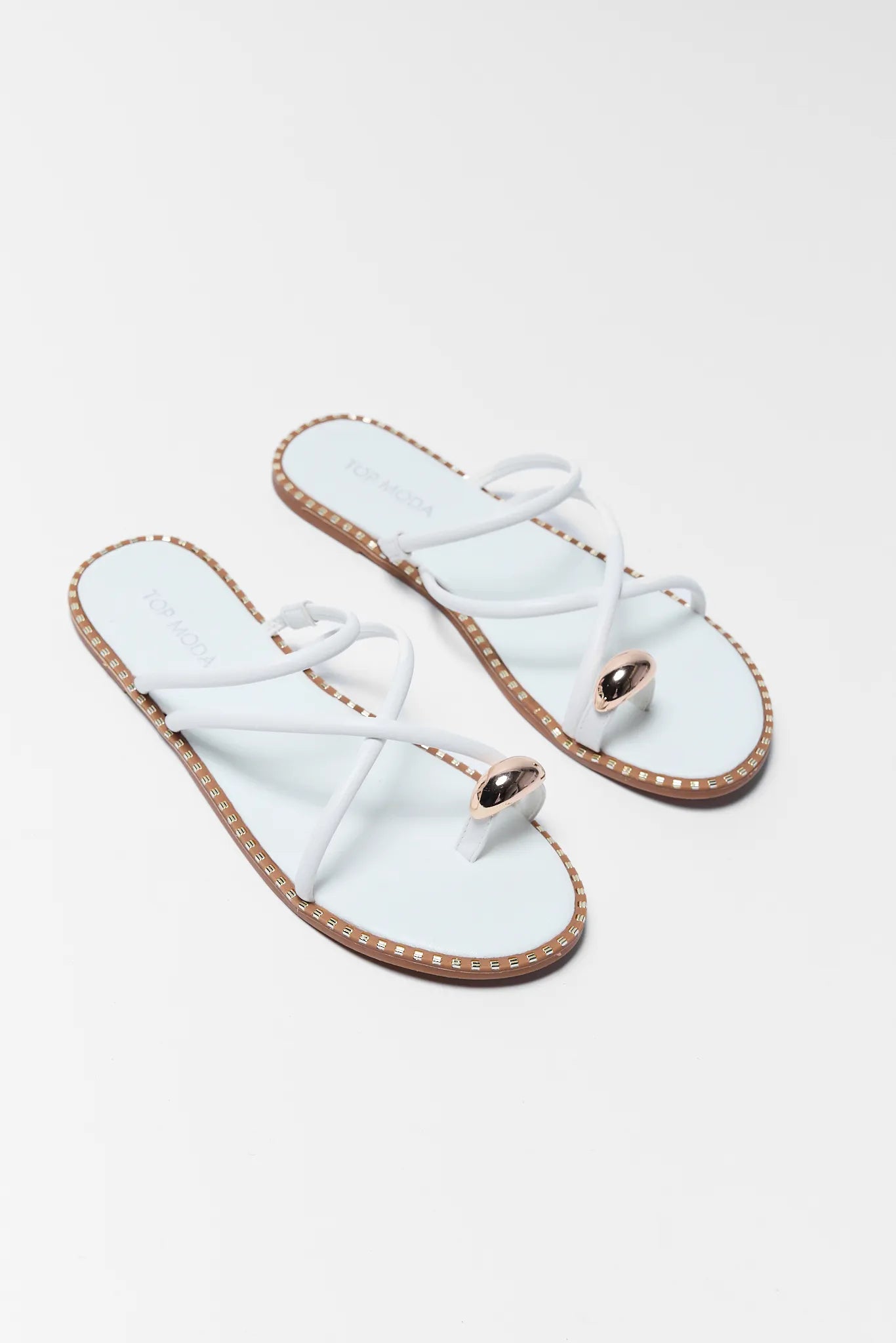 Pair of white sandals with gold accents on a light gray background