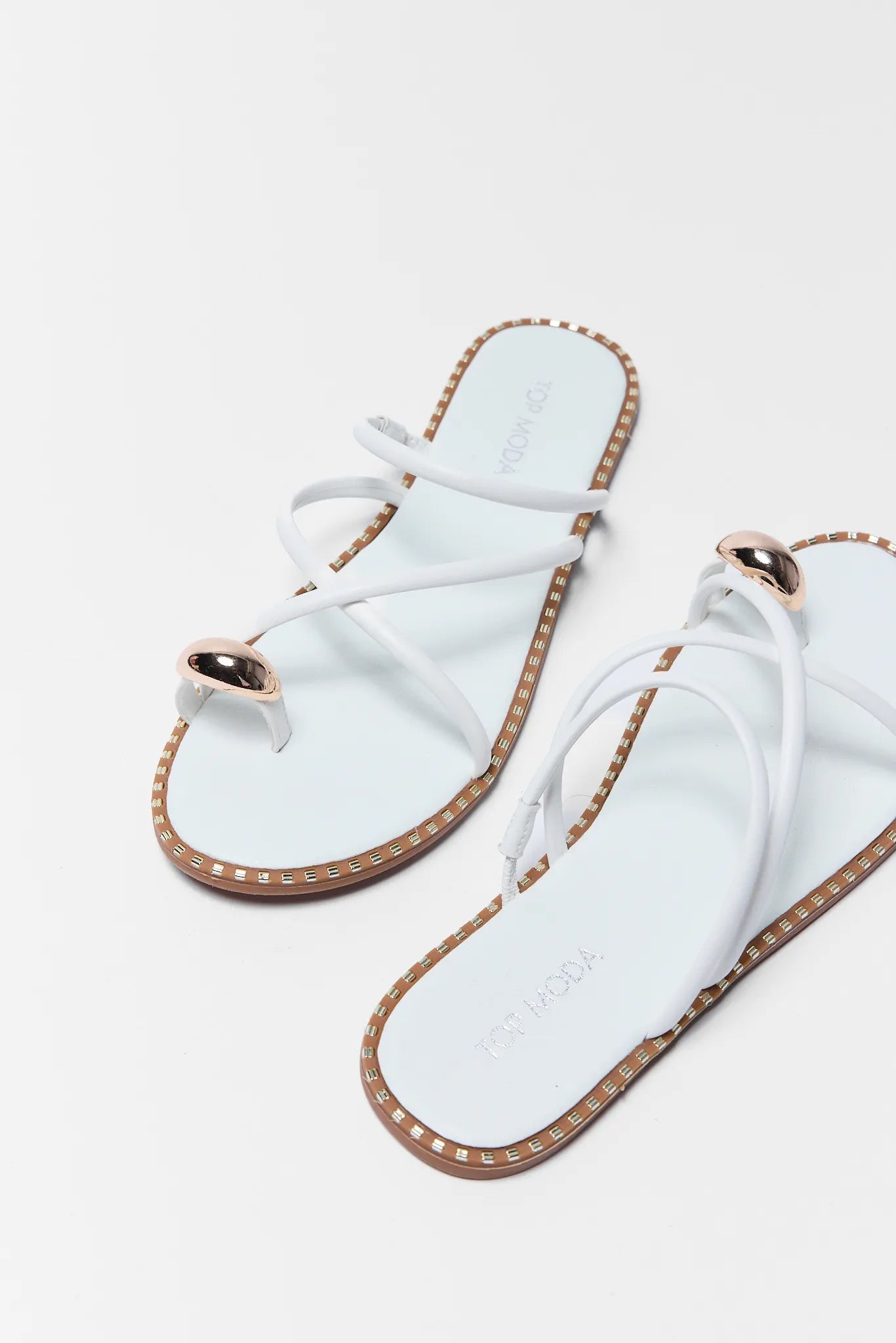 Pair of light white sandals with gold accents on a white background